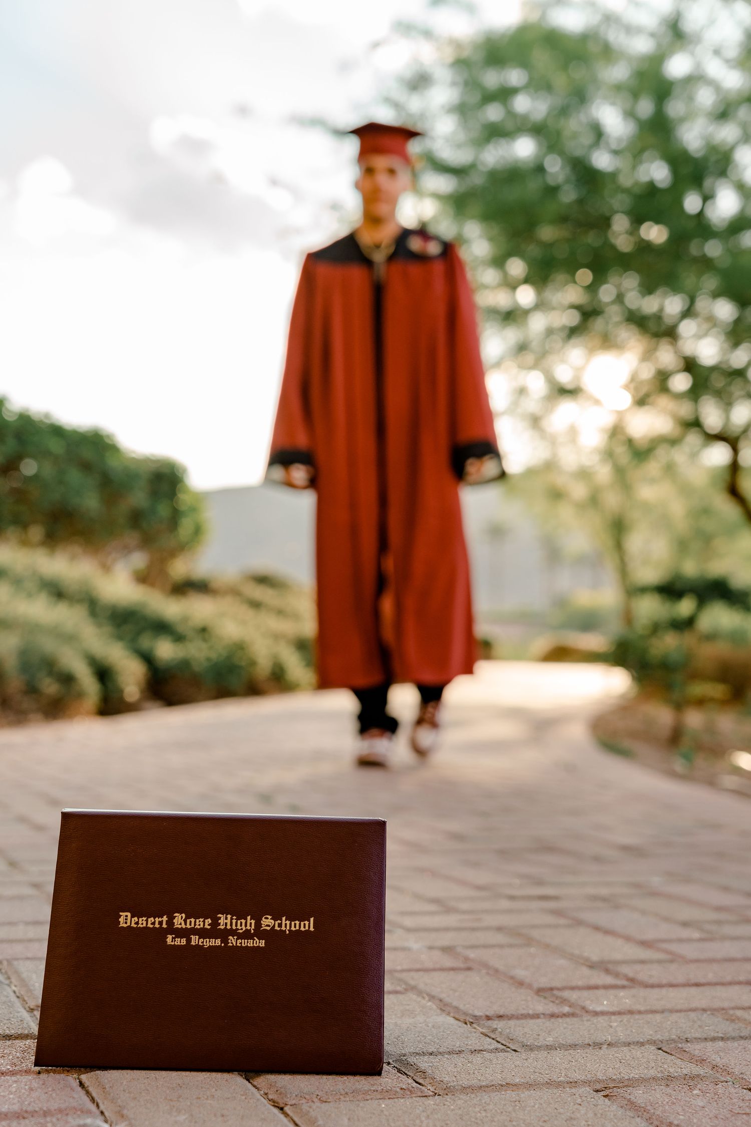 Desert Rose High School Las Vegas graduation diploma displayed with graduate in red cap and gown.