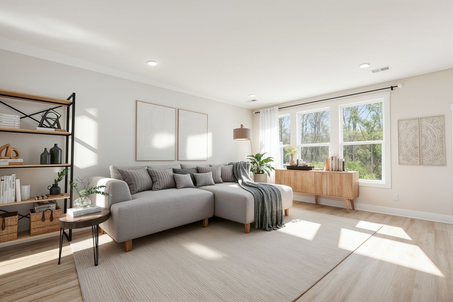 Bright modern living room with gray sectional sofa, wood shelving, and large windows flooding the space with natural light.
