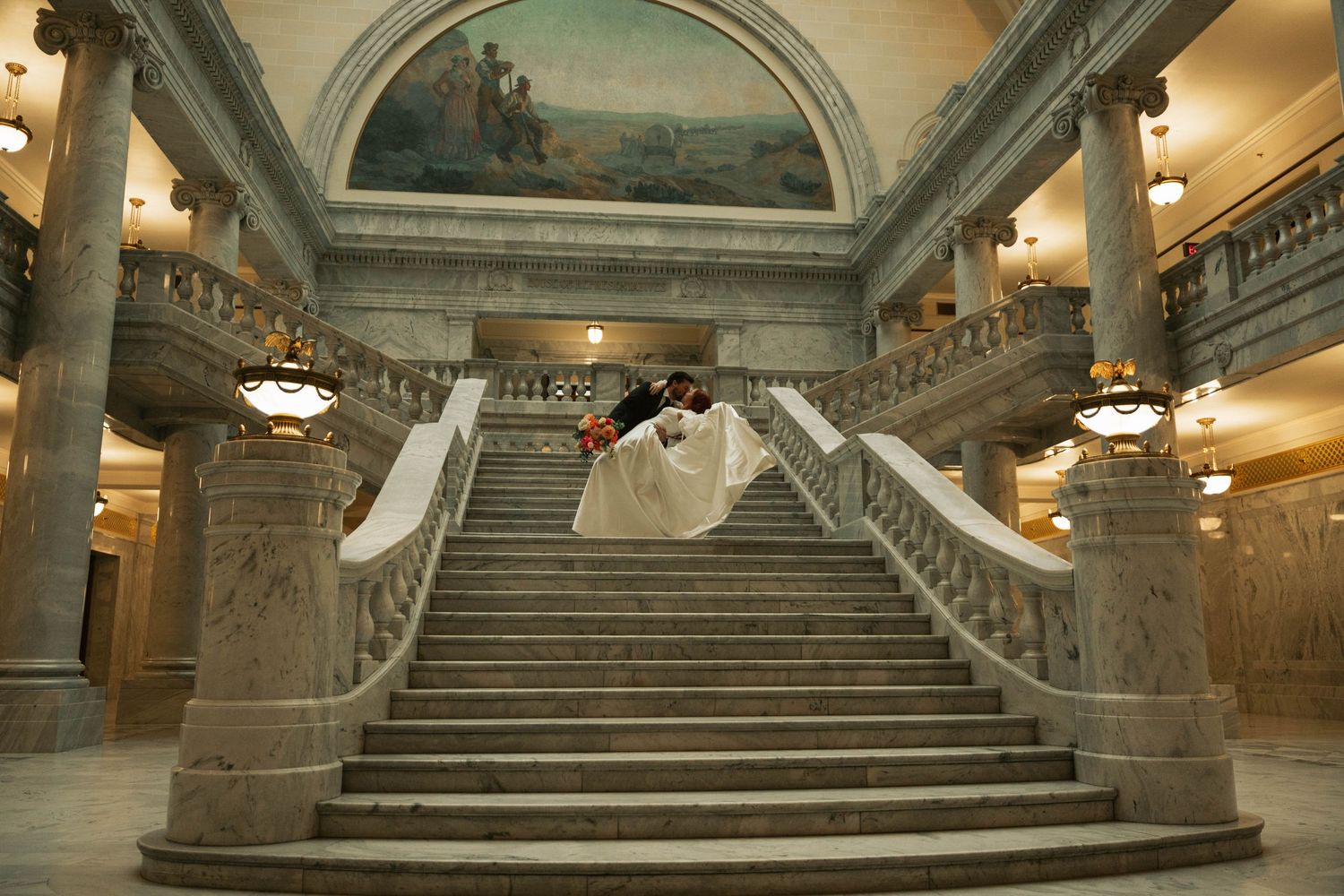 Grand marble staircase in a historic building with ornate architectural details and dramatic lighting.