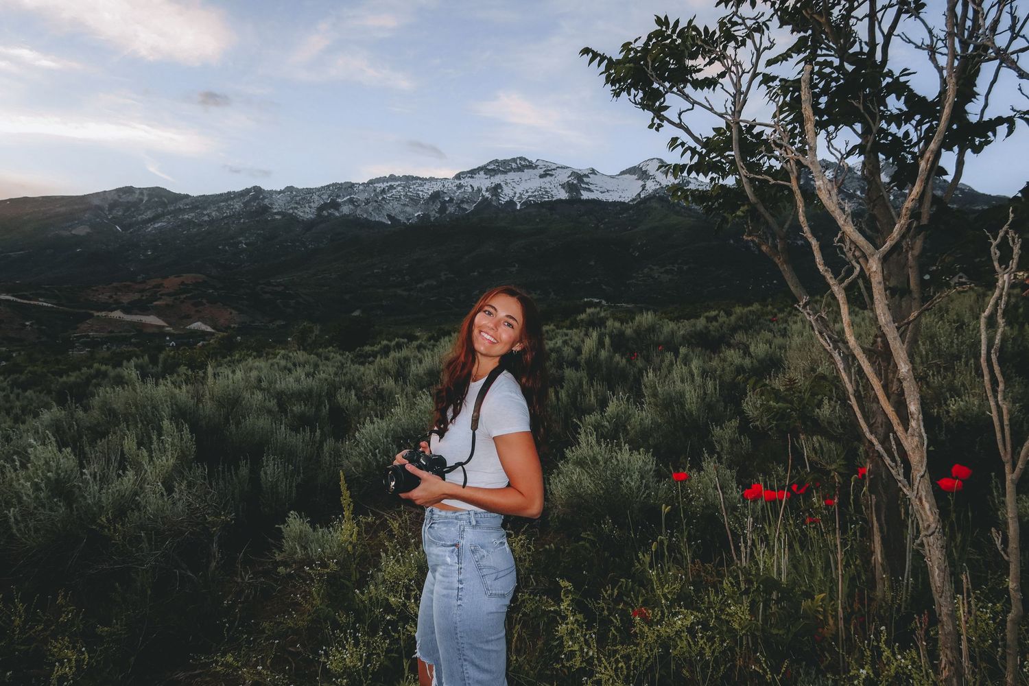 A playful portrait session in a mountain meadow with red poppies and evergreen trees.