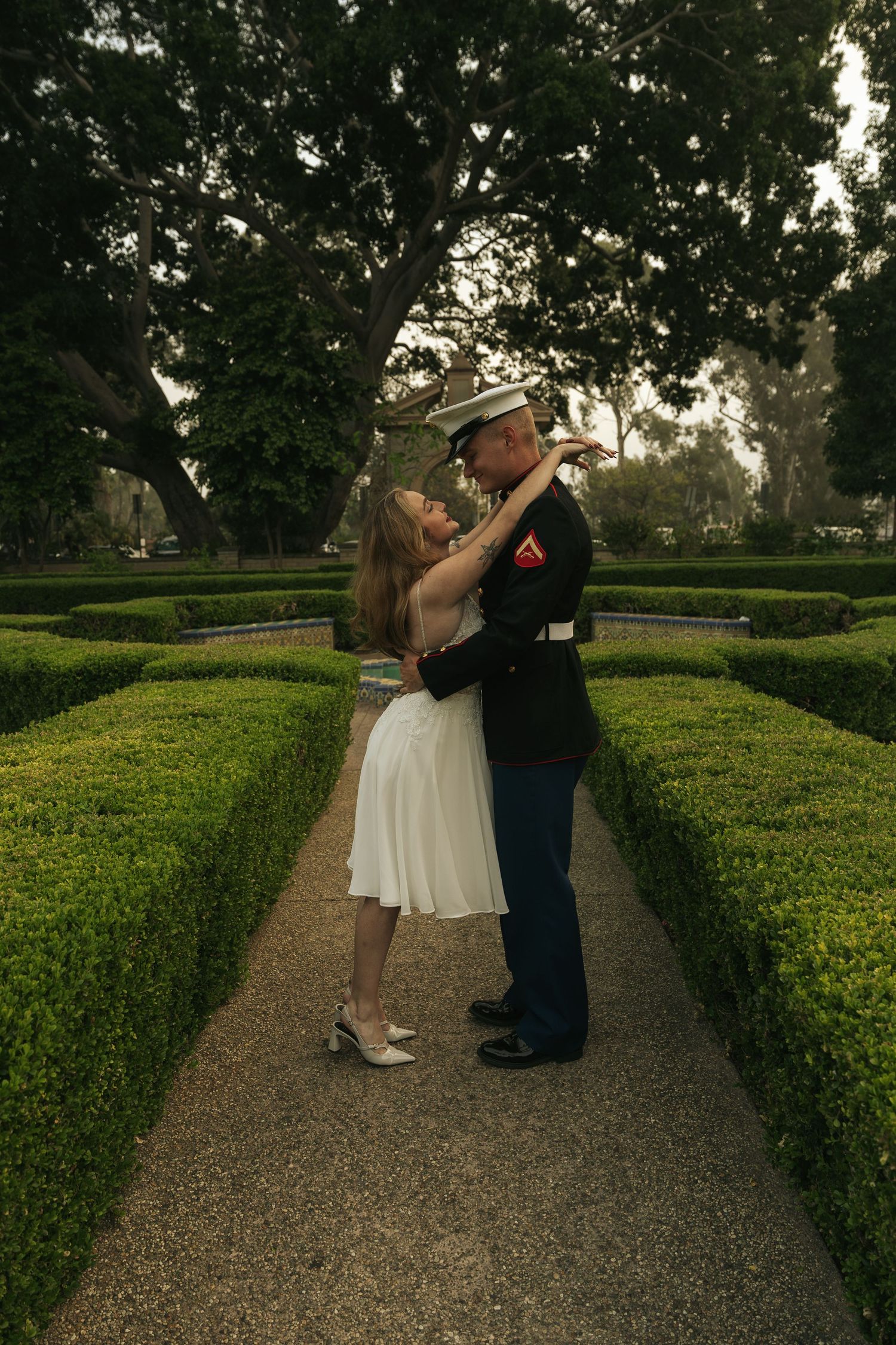 A romantic garden wedding photoshoot with manicured hedges and gravel paths.