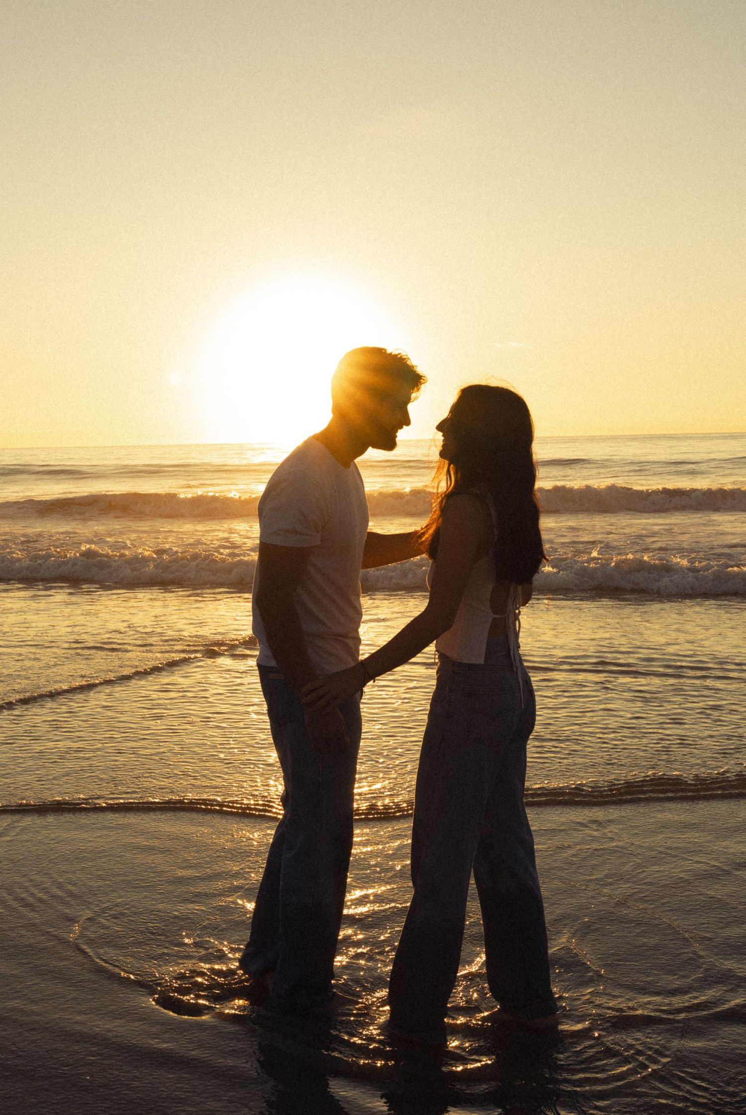 Couple sharing an intimate moment on Southern California beach during golden hour.