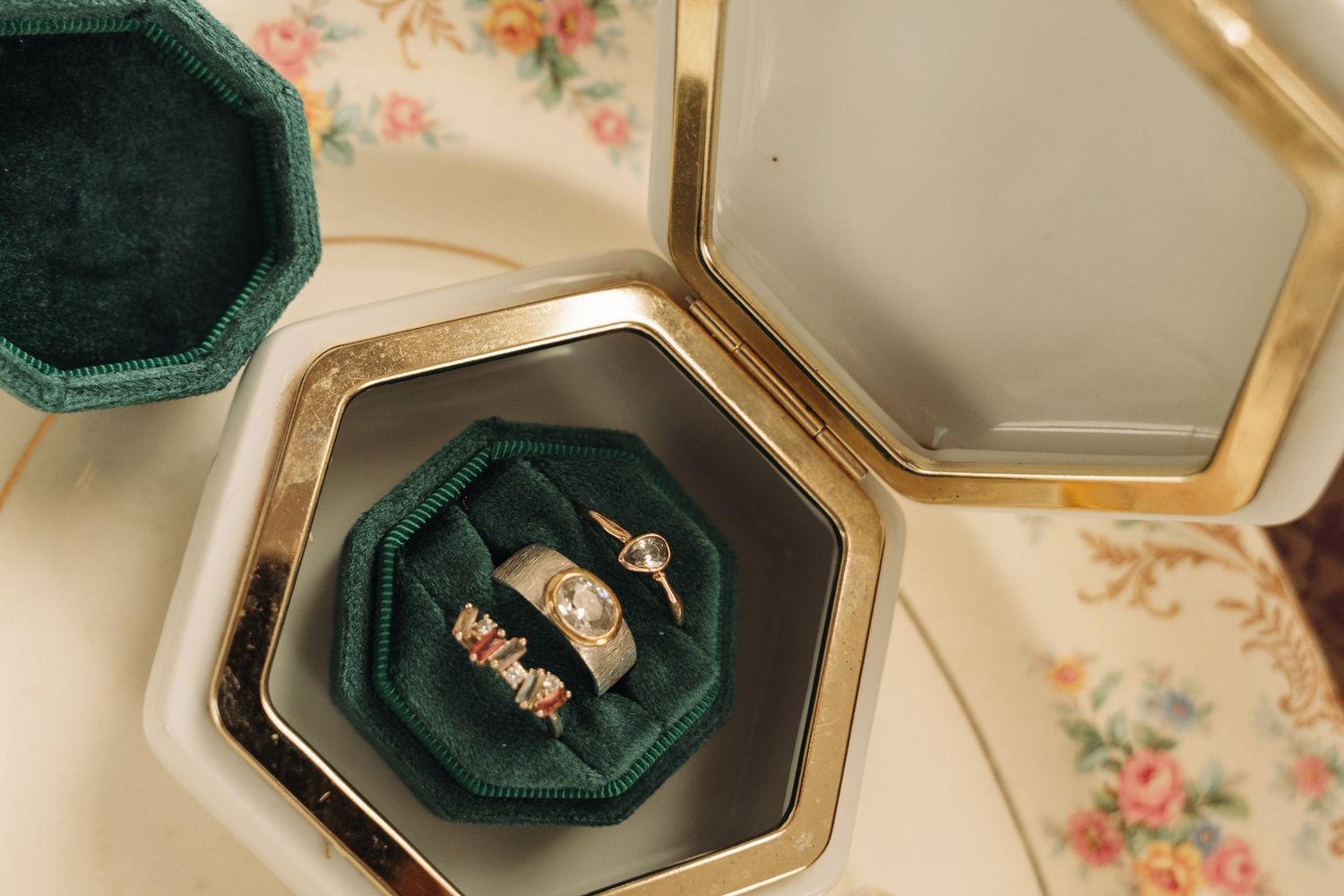 Wedding rings nestled in an emerald green velvet ring box with gold trim.