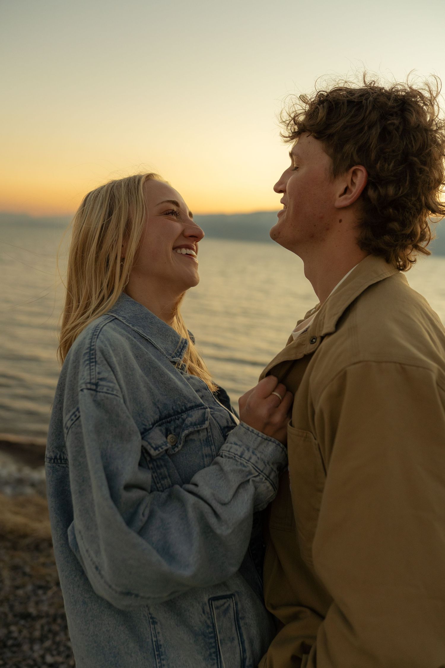 Couple laughing together by the ocean during sunset.