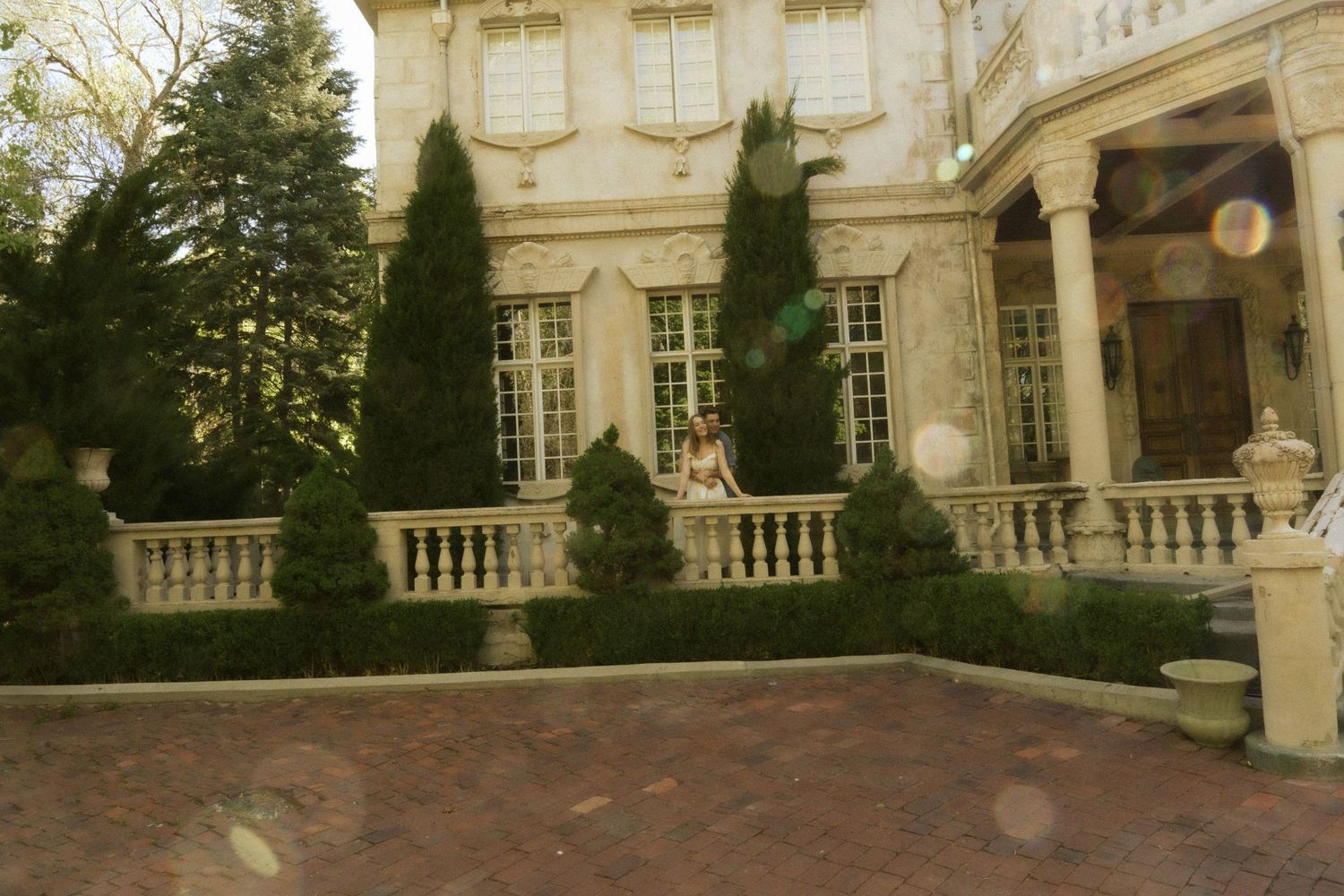 An elegant historic mansion exterior with classical architecture and manicured cypress trees.