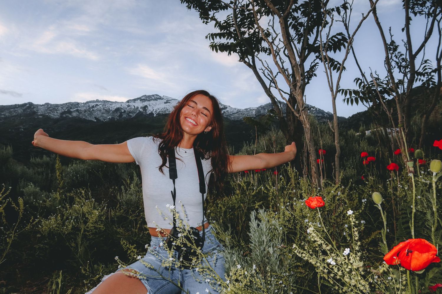 A joyful moment captured in a mountain meadow with red poppies and distant peaks.