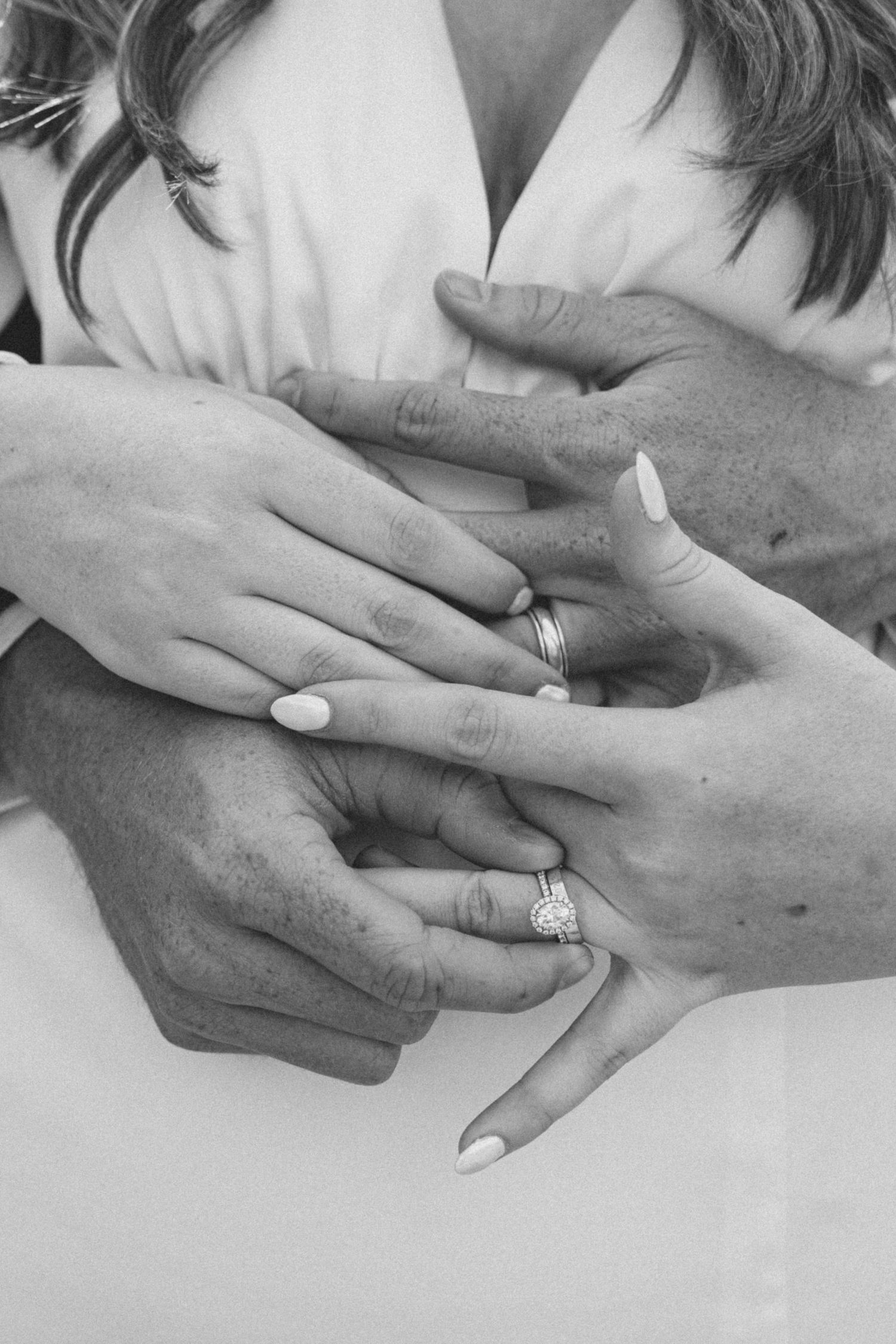 Close-up of hands exchanging wedding rings in black and white photography.