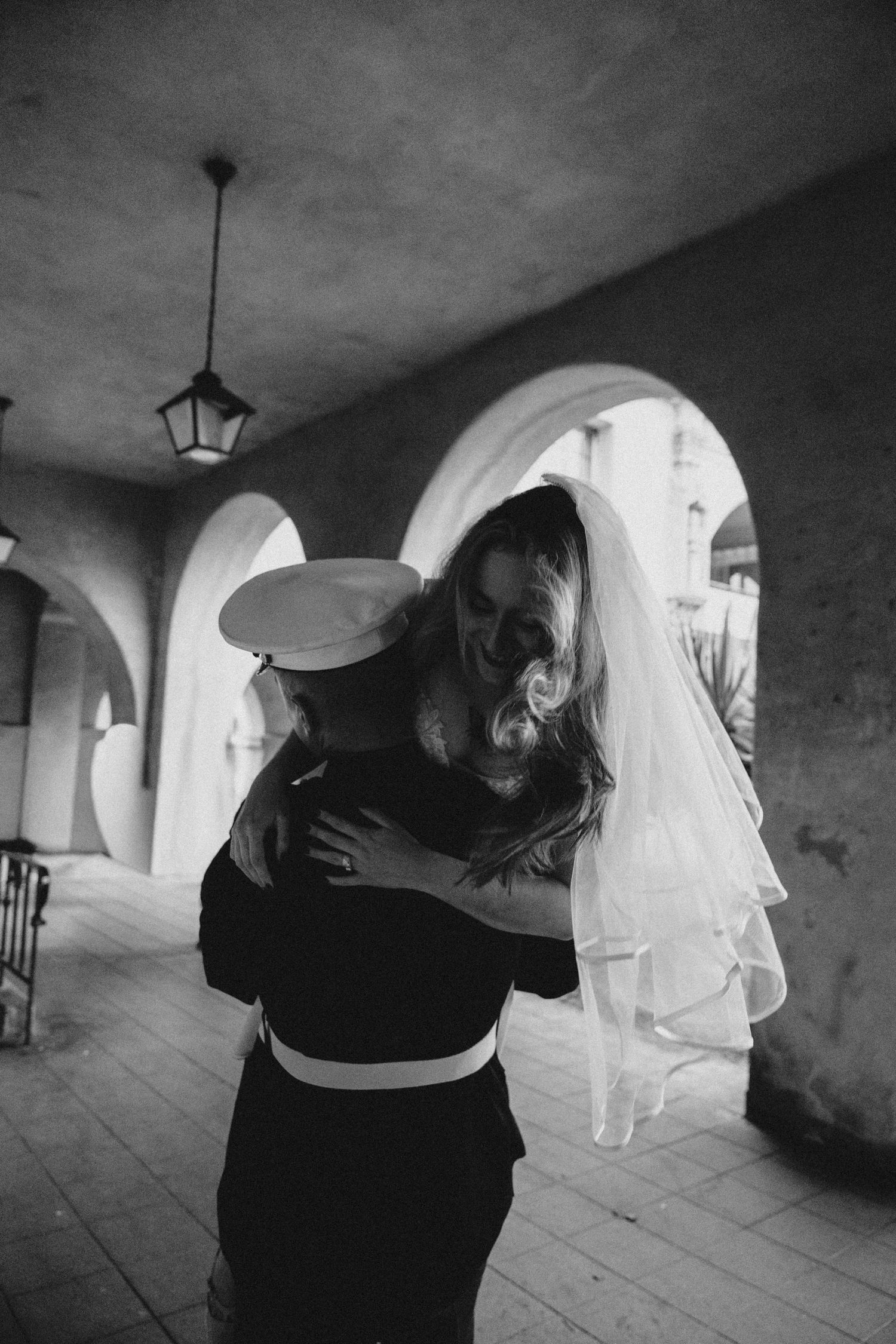 Black and white wedding photos taken in a covered colonnade with arched architecture.