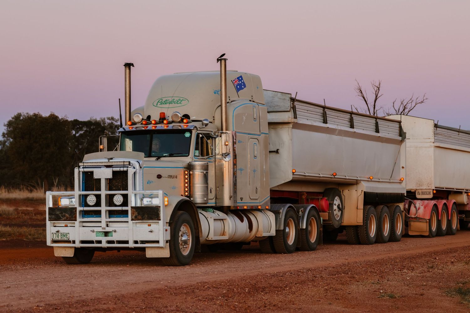A series of vintage trucks and trailers lined up in a row against a retro-tinted landscape backdrop.