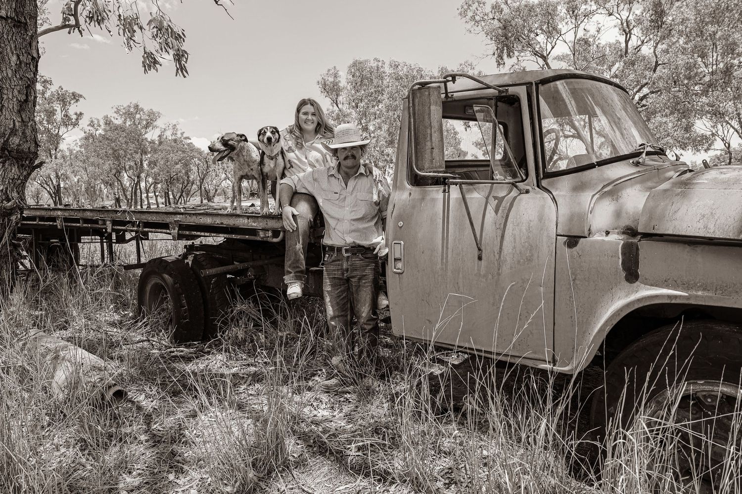 A vintage black and white photo showing people with an old truck in a rural setting.