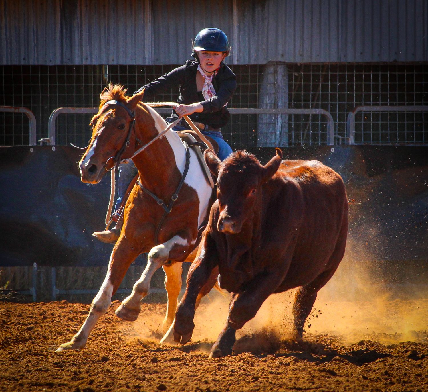 Dramatic action shot of horses galloping through dusty arena during western competition.