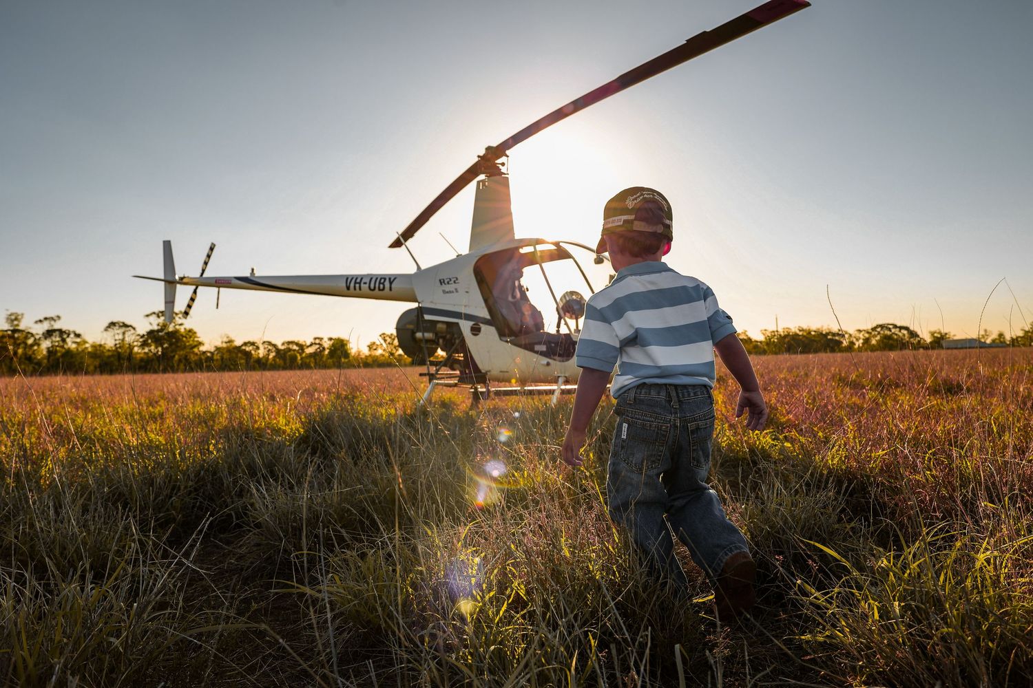 Remote control airplane enthusiasts prepare their model aircraft for flight in a golden field at sunset.
