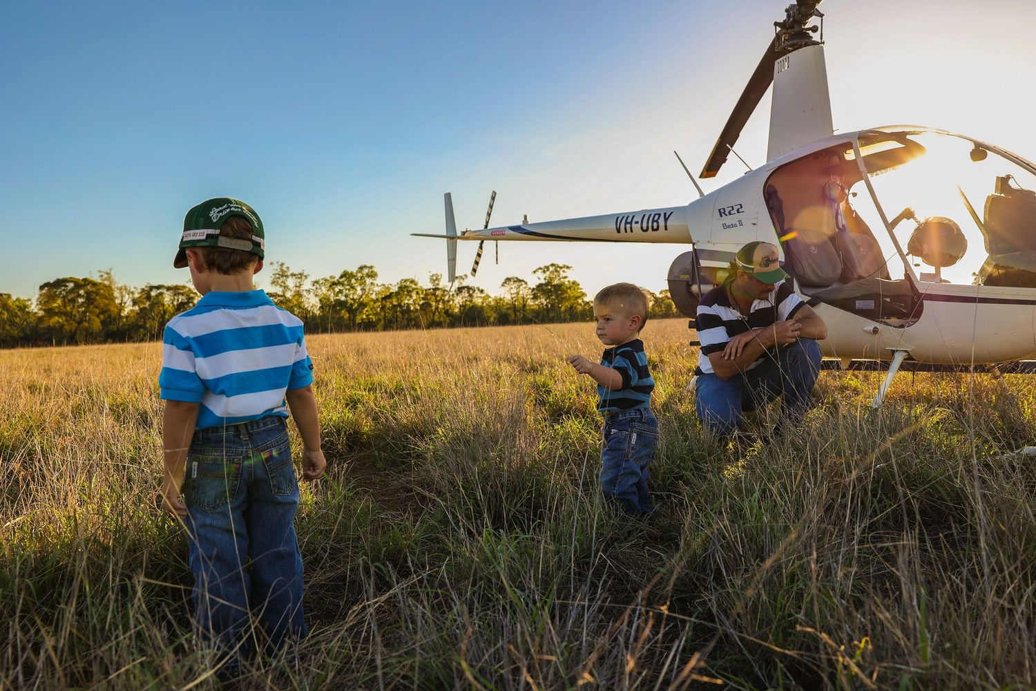 Model airplane being readied for takeoff in a grassy field during golden hour.
