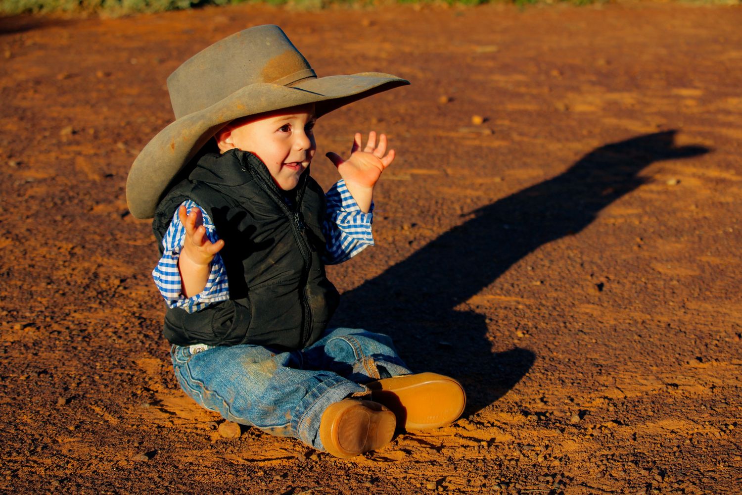 A sequence of shadows cast on reddish dirt ground shows someone falling backwards in stages.
