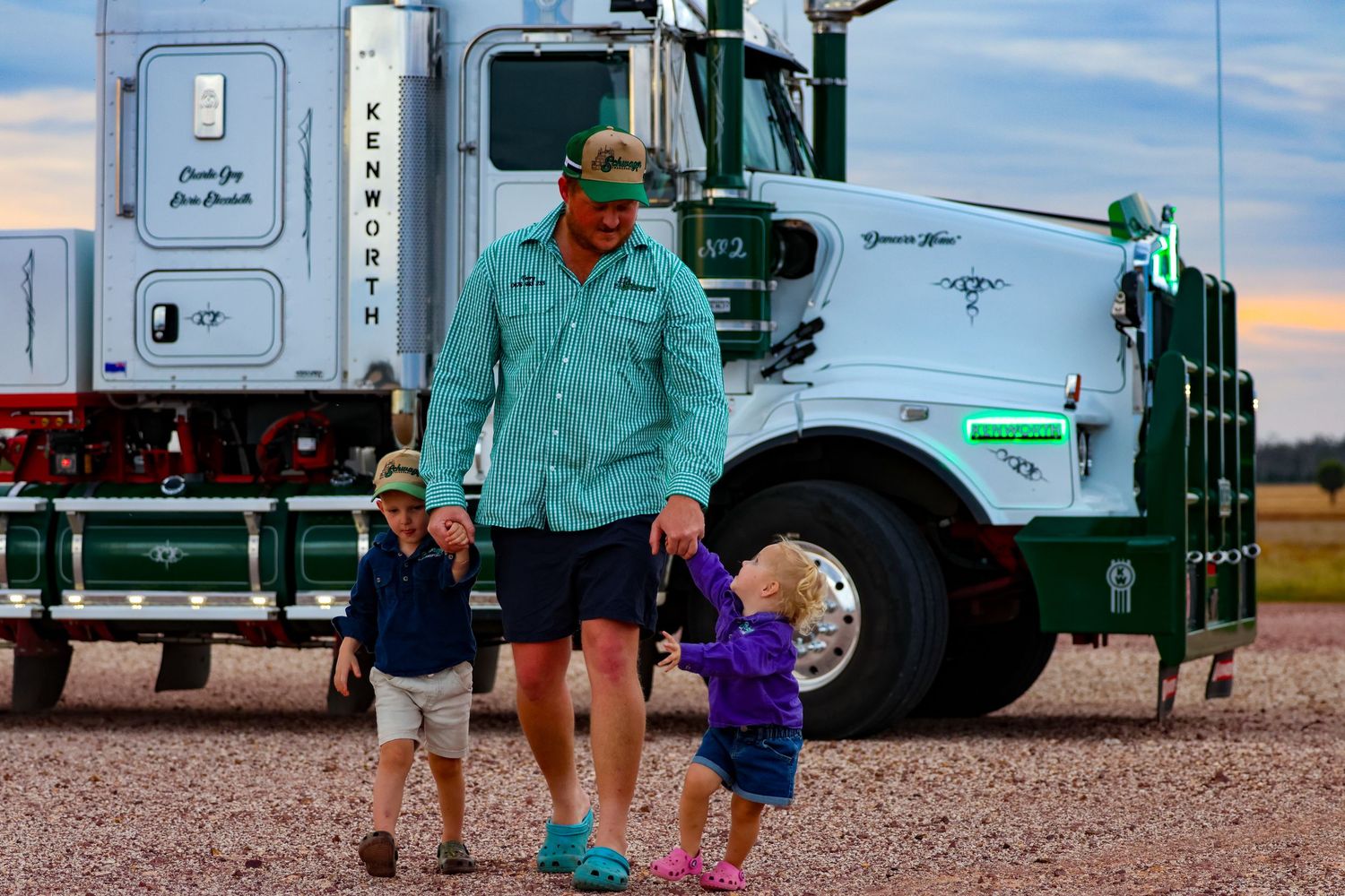 Agricultural workers gather near large grain trucks during harvest season in a rural farming field.