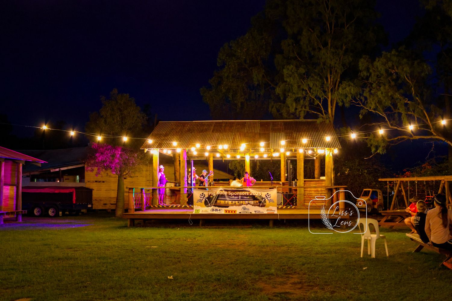 String lights illuminate a rustic outdoor venue at dusk creating a warm and inviting atmosphere for evening gatherings.
