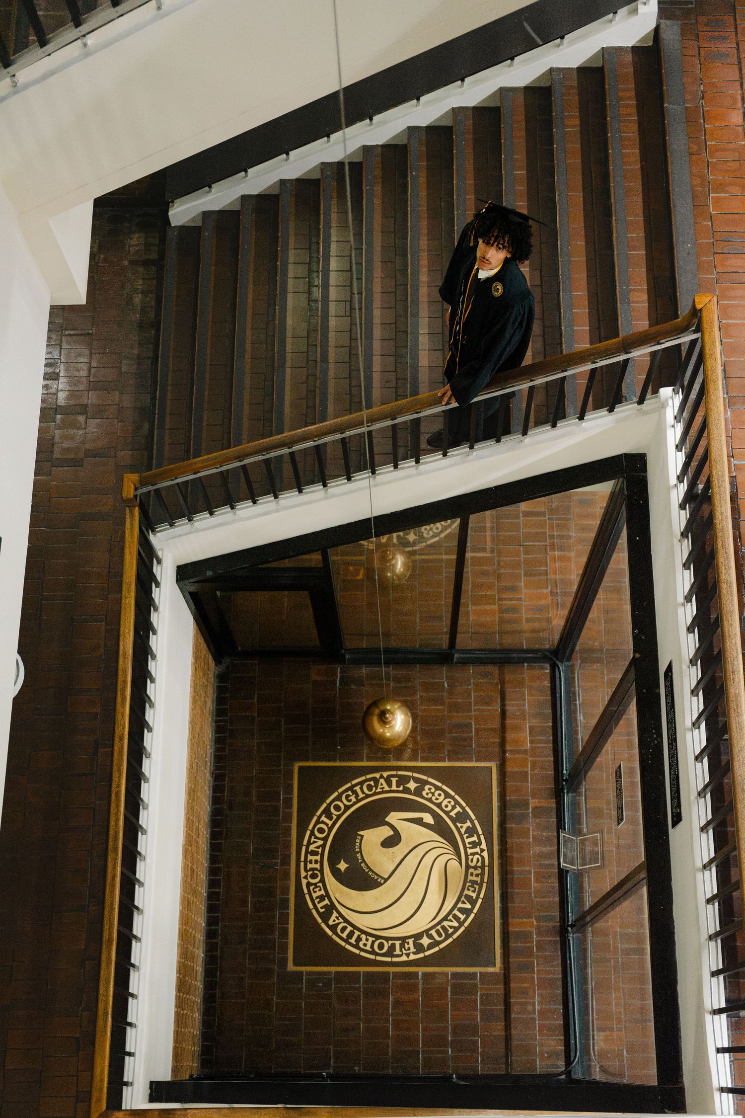 Aerial view of a stairwell at Florida Bible Institute featuring a decorative logo on brick floor below.
