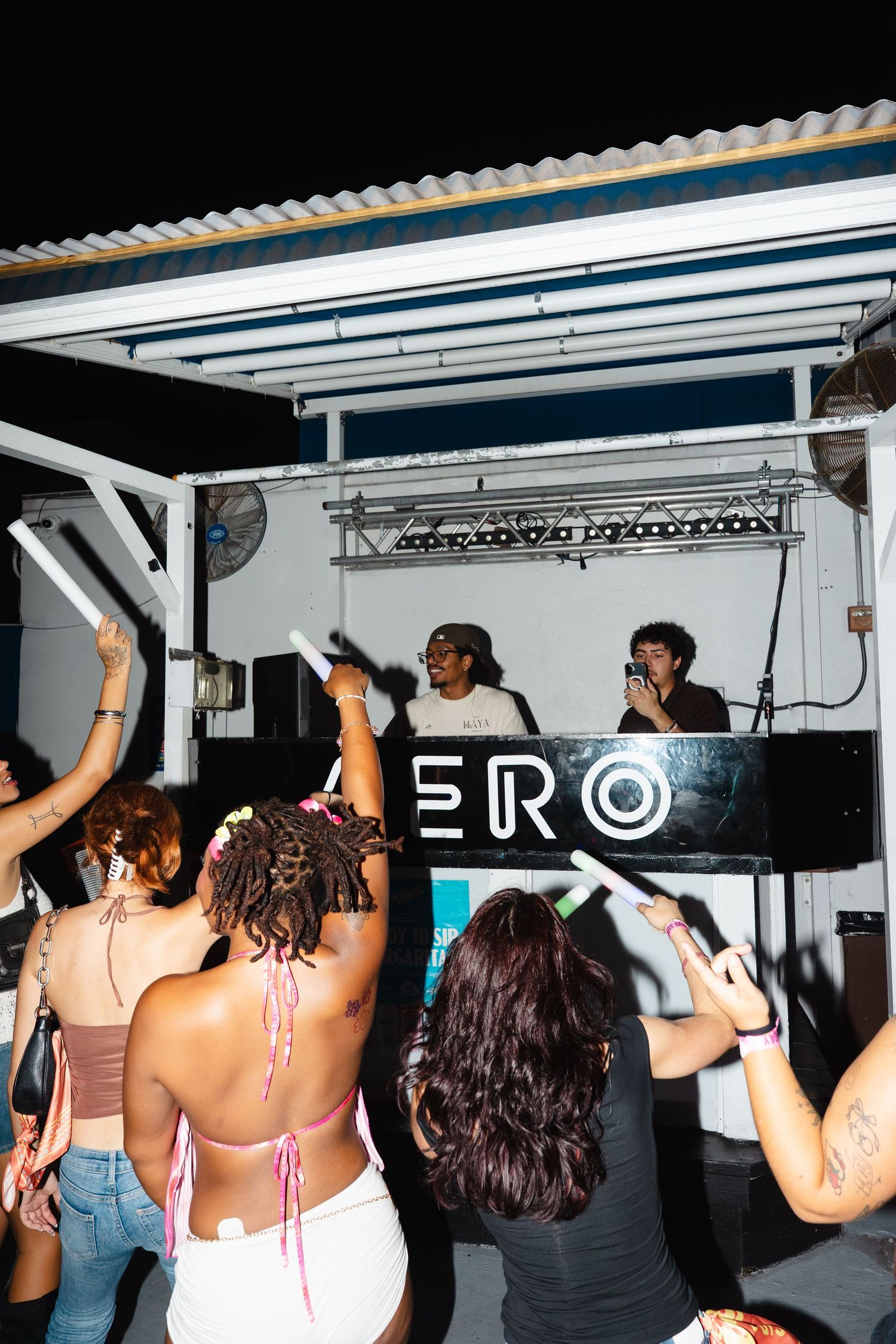 Crowd dancing at outdoor night party in front of DJ booth with ERO signage on stage.