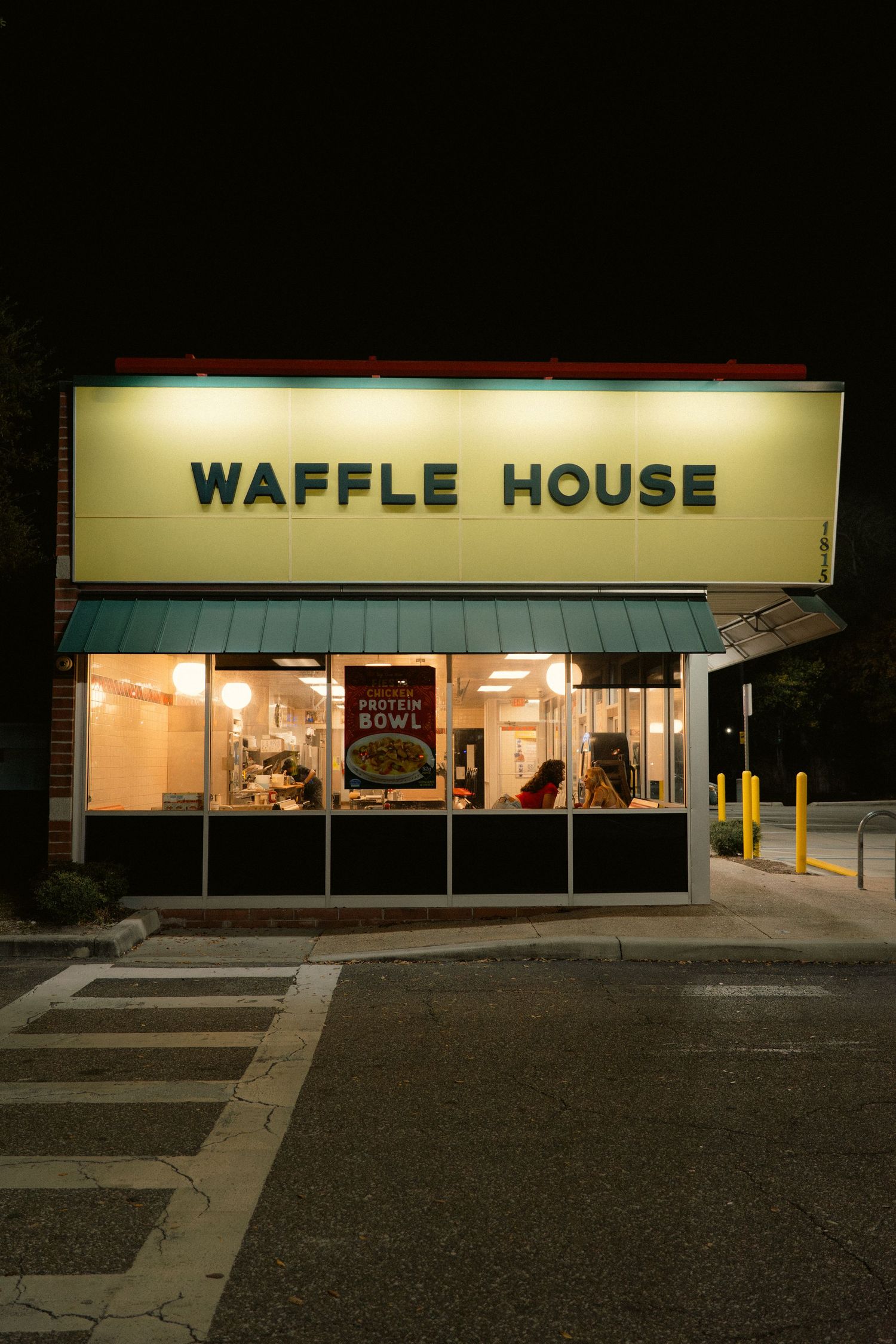 Waffle House restaurant exterior illuminated at night with glowing signage and protein bowl advertisement in window.