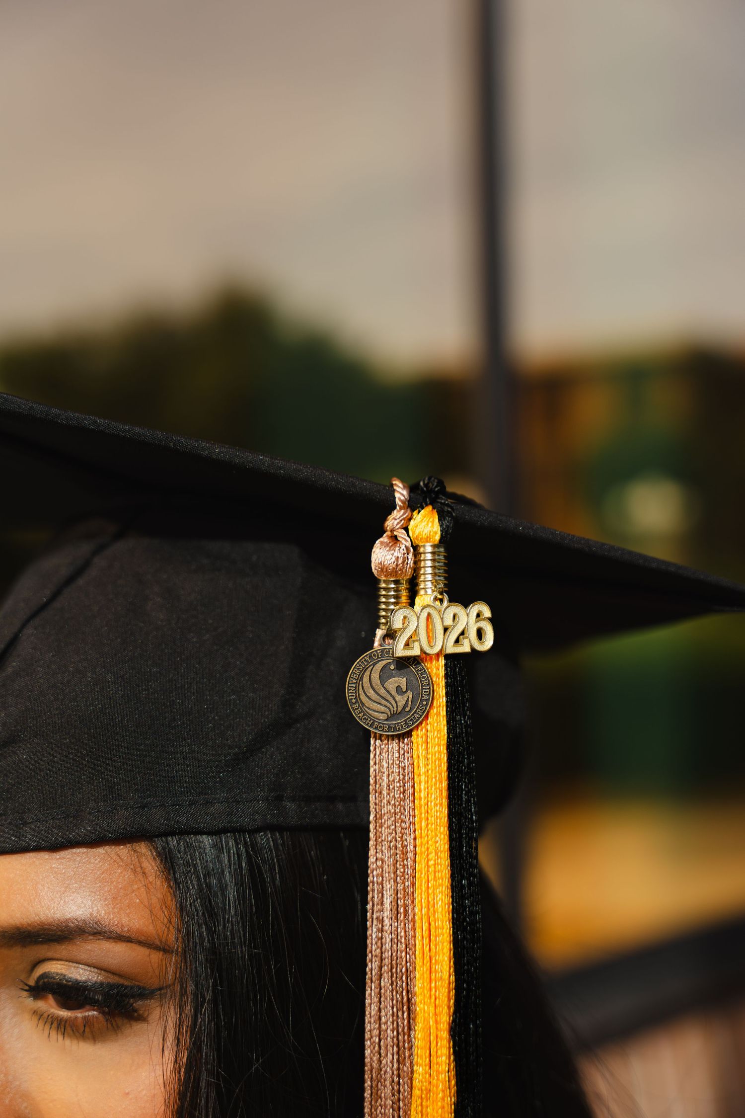 Close-up of a graduation cap with a gold 2026 tassel charm worn by a young woman at a commencement ceremony.