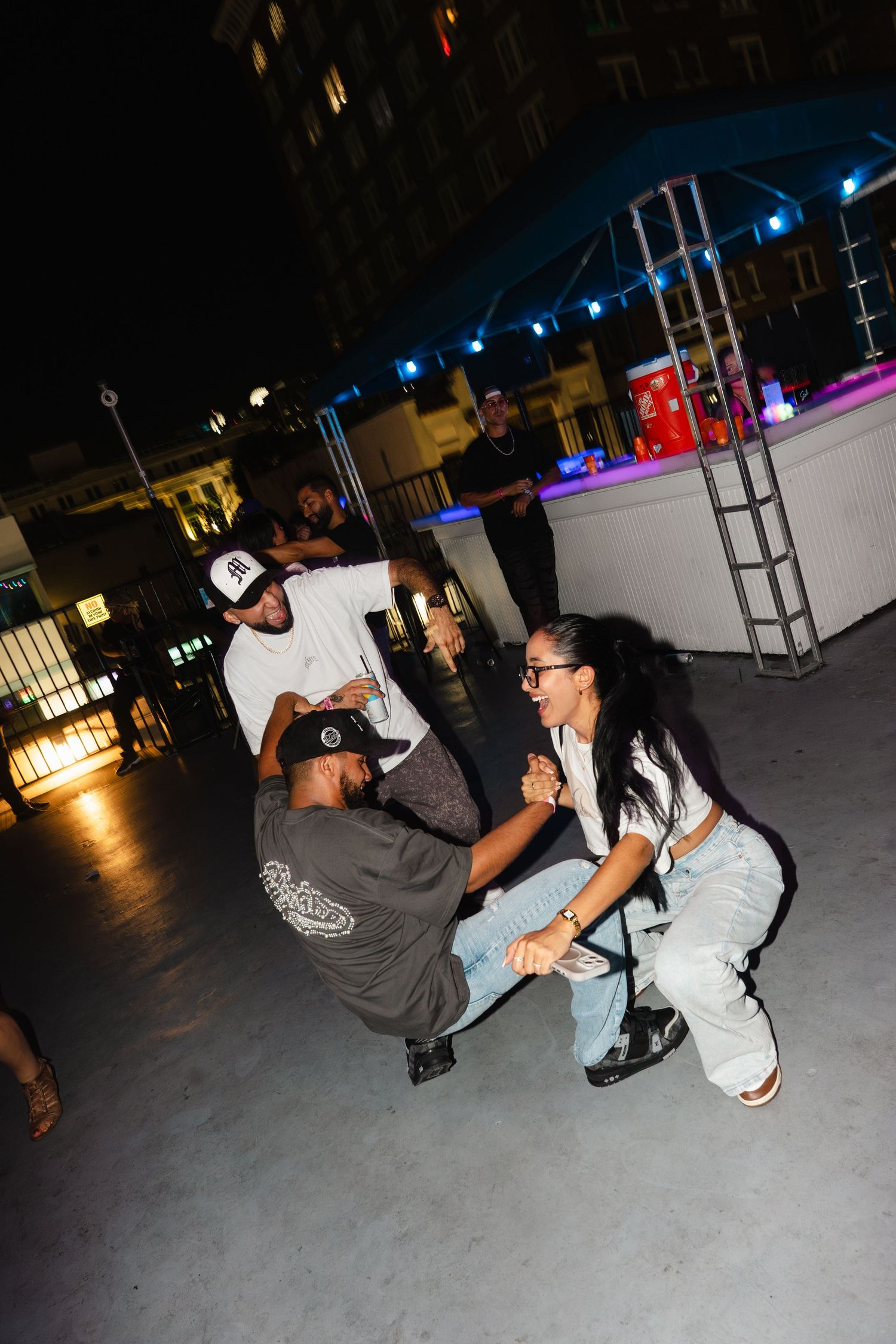 People dancing and socializing outdoors at a night event on a rooftop venue.