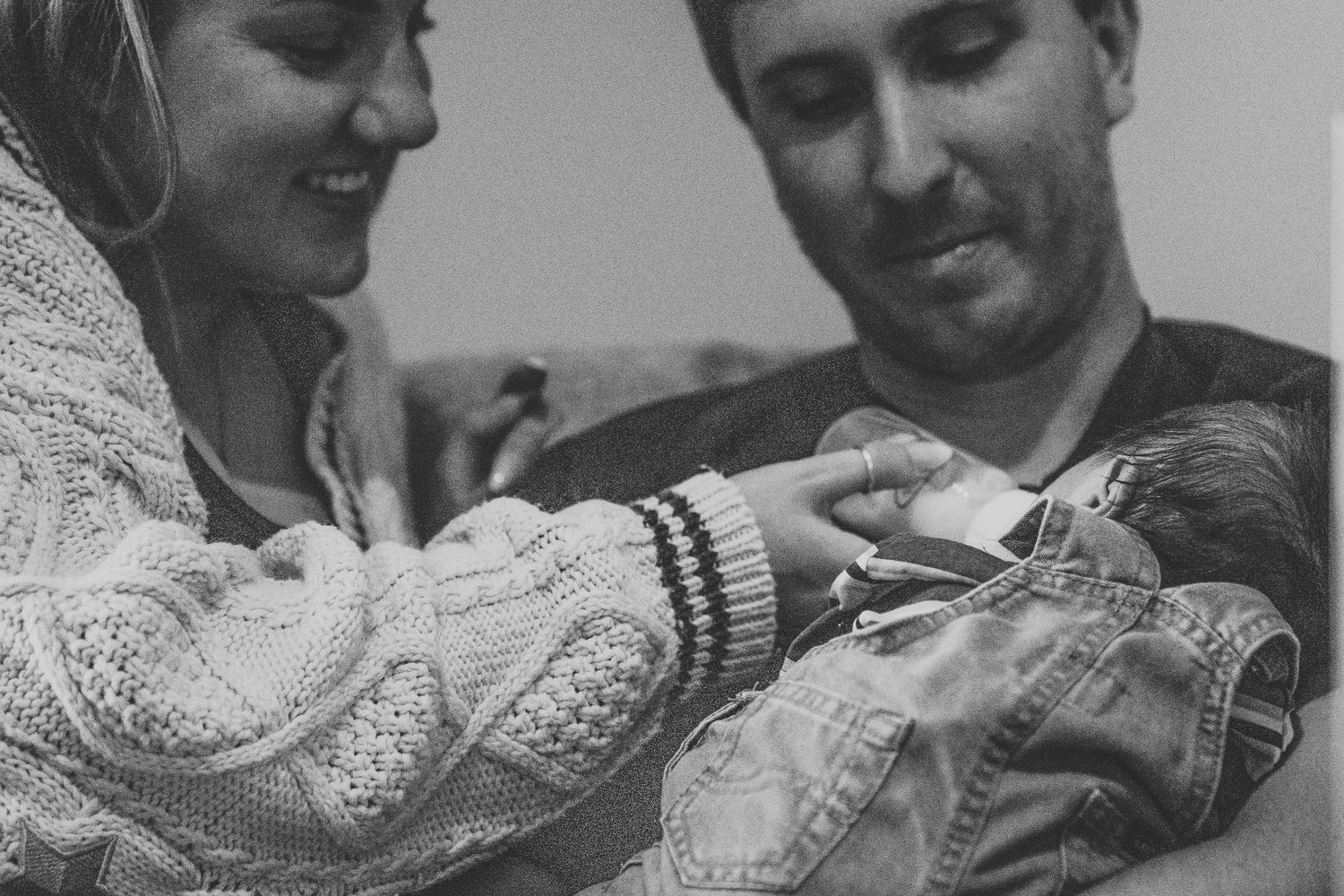Black and white photo of parents admiring their newborn baby together.