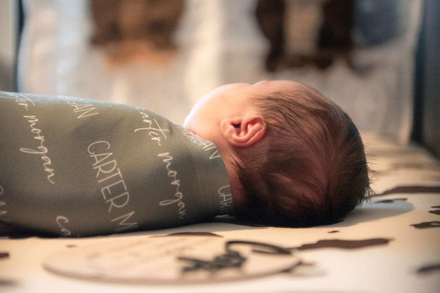 Sleeping newborn baby Carter Morgan swaddled in personalized teal blanket.