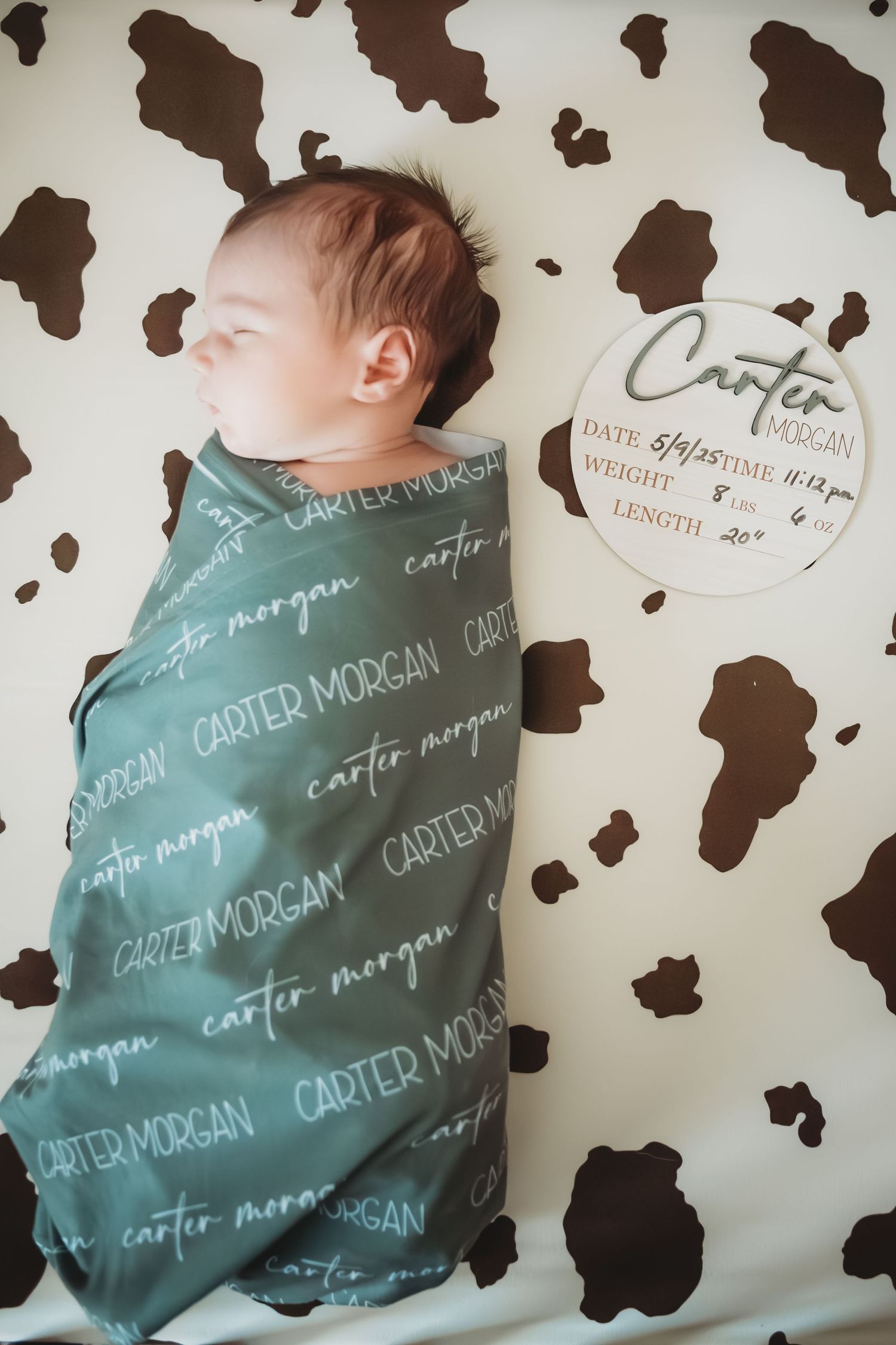 Newborn baby Carter Morgan swaddled in personalized blanket with birth stats sign.