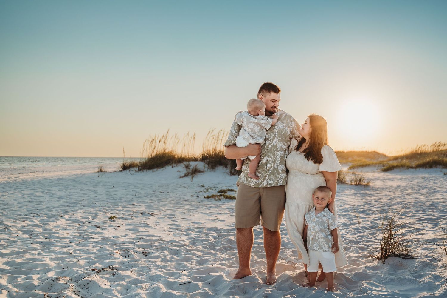 Family enjoying a golden sunset beach photo session on white sand dunes.