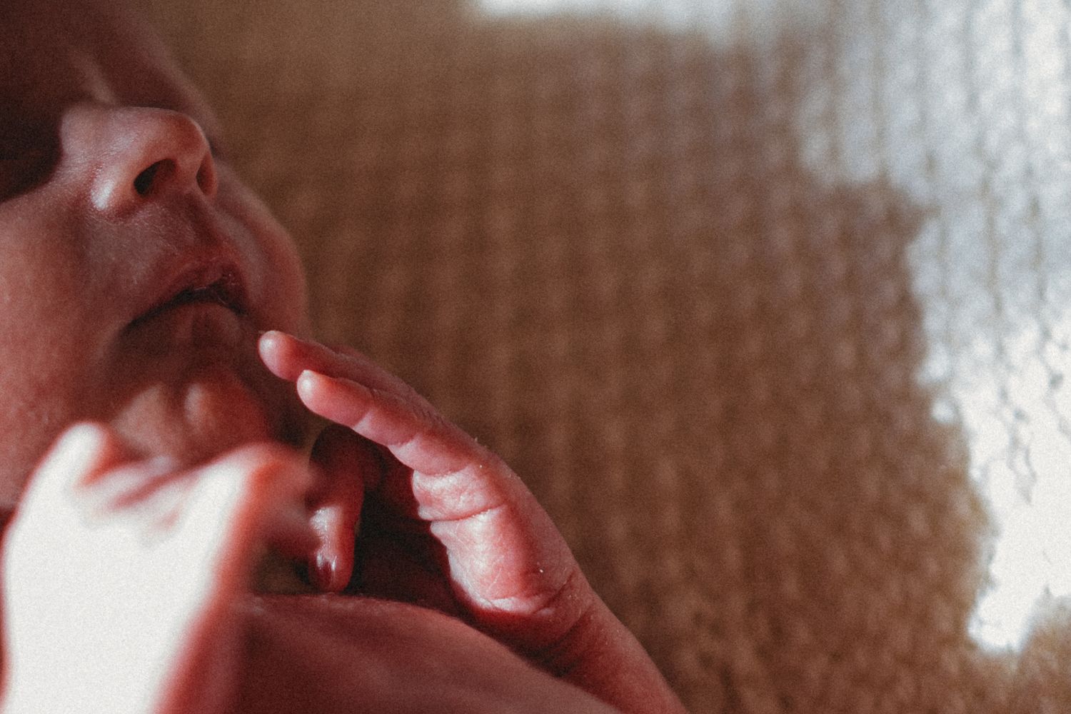 Close-up of a peaceful newborn baby's face and tiny fingers.