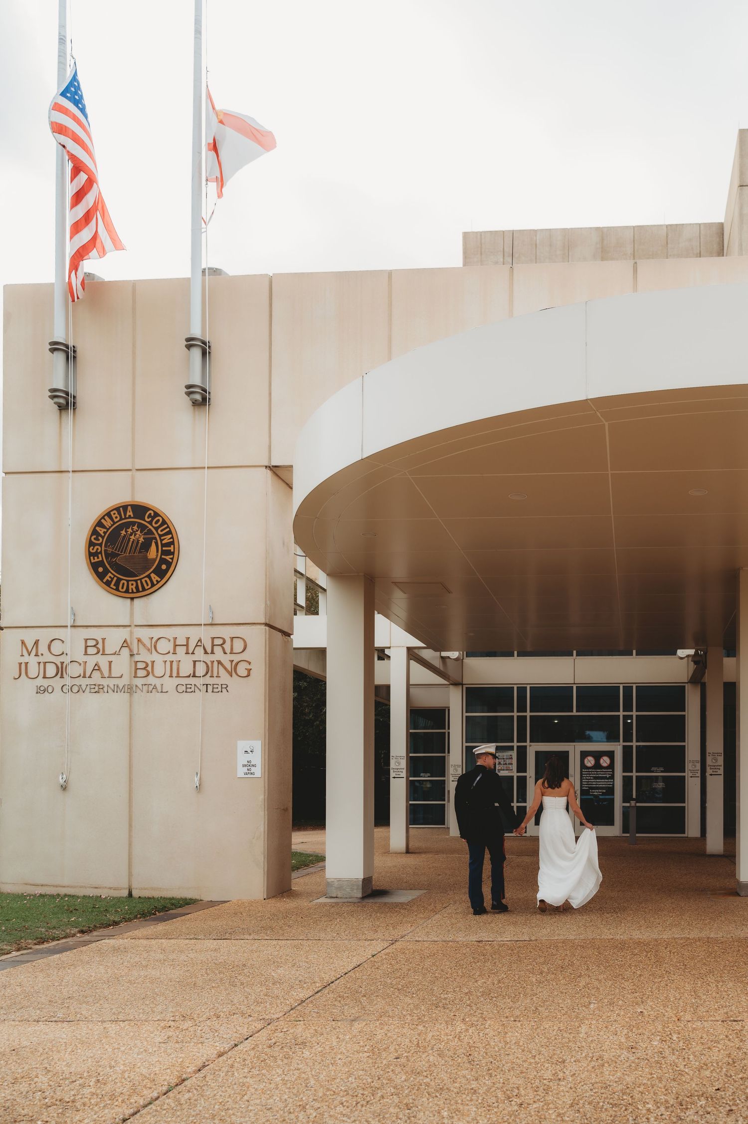 Couple in wedding attire walking into M.C. Blanchard Judicial Building in Escambia County, Florida.