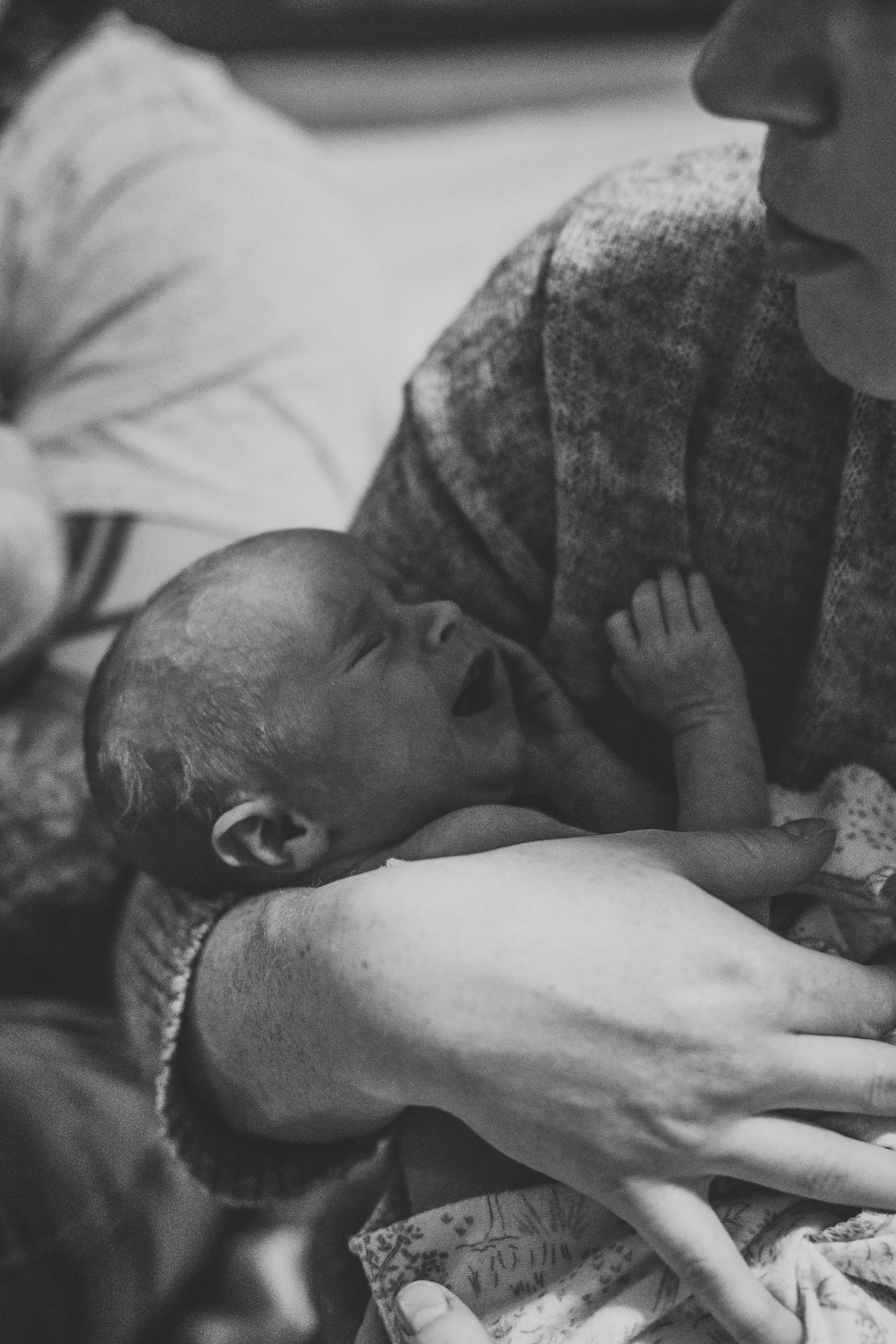 Black and white close-up of newborn baby resting on mothers chest after birth.