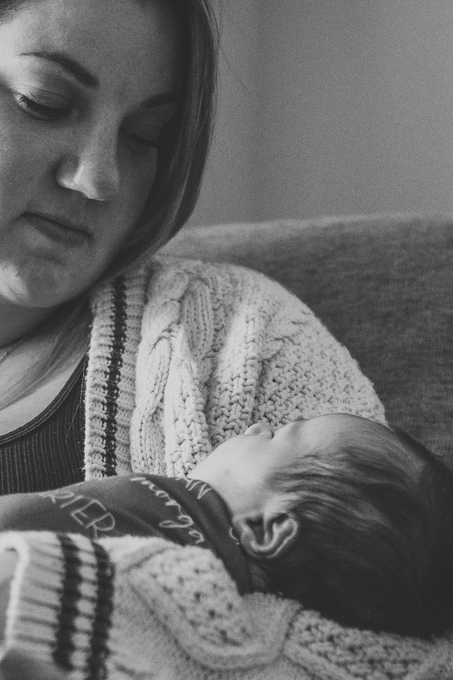 Black and white photo of new mother tenderly cradling her sleeping newborn baby.