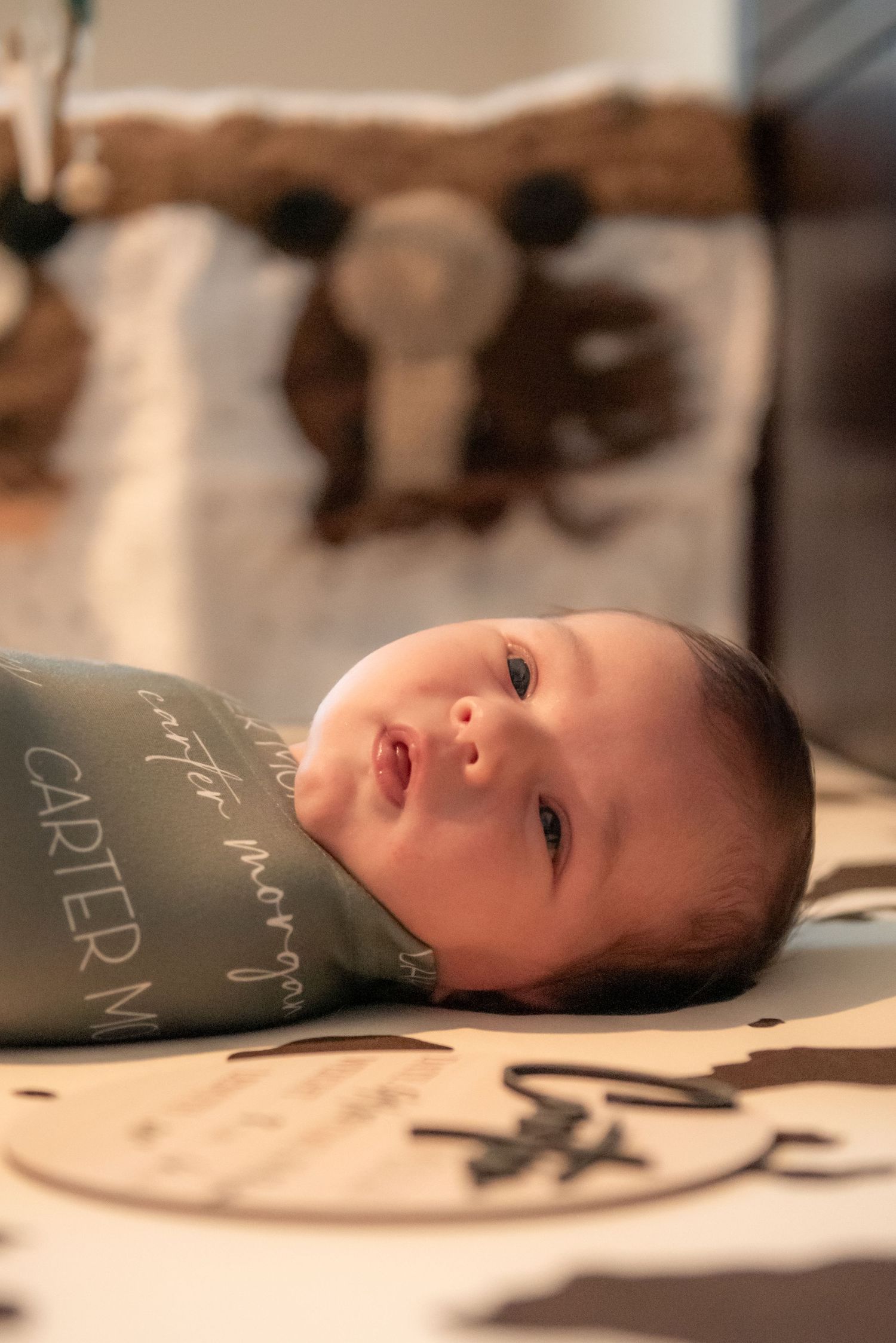Alert newborn baby Carter Morgan swaddled in personalized teal blanket.