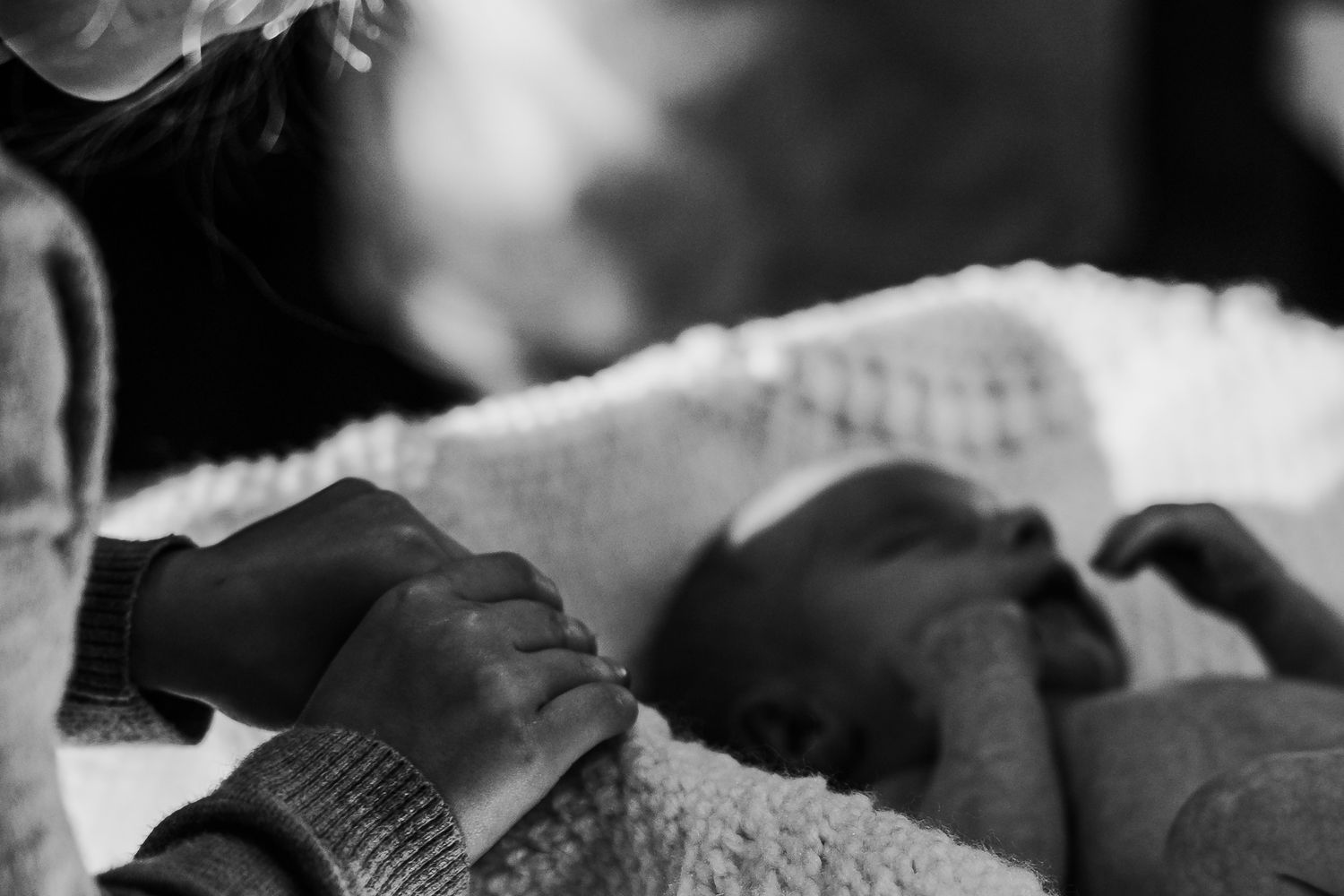 Black and white photo of a parent tenderly holding a sleeping newborn baby.