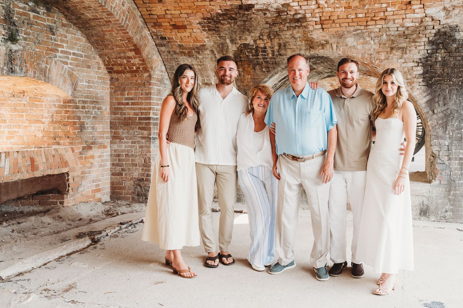 Family of six posing together inside a historic brick arched building with natural light.