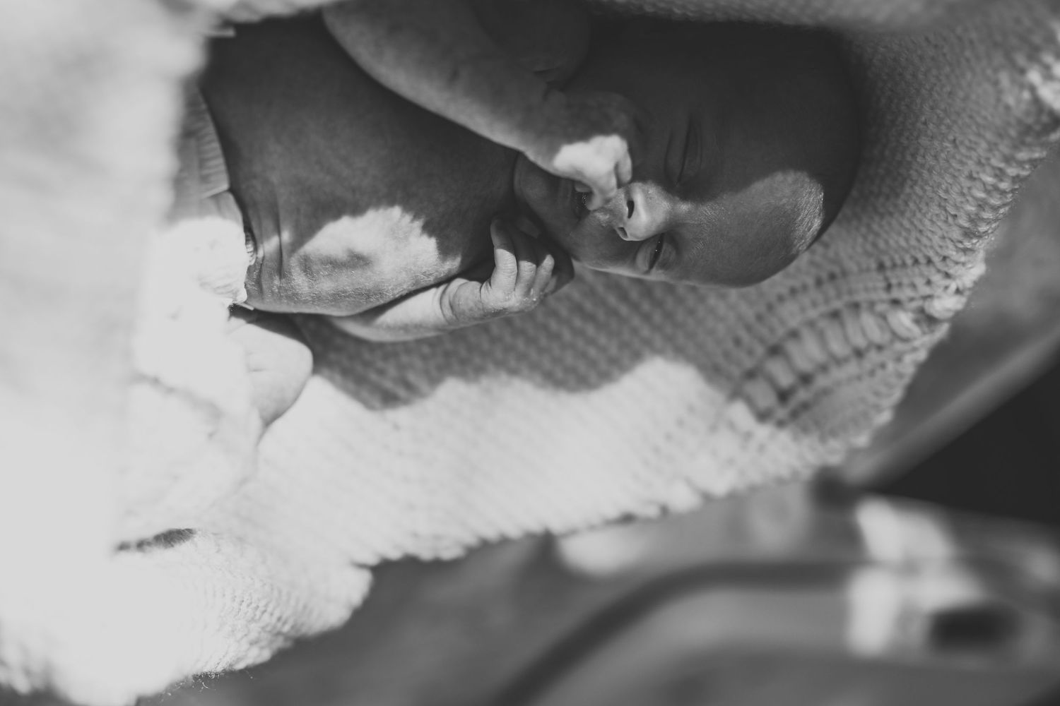 Black and white close-up of a newborn baby's tiny hand grasping fabric.