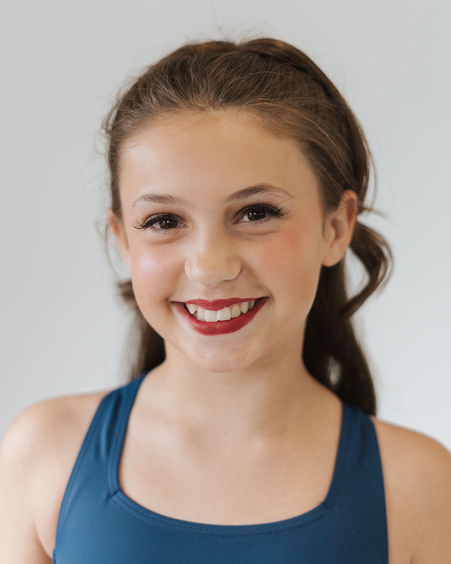 Sequence of four closeup photos showing a bright smile and warm expression in a blue top against white background.