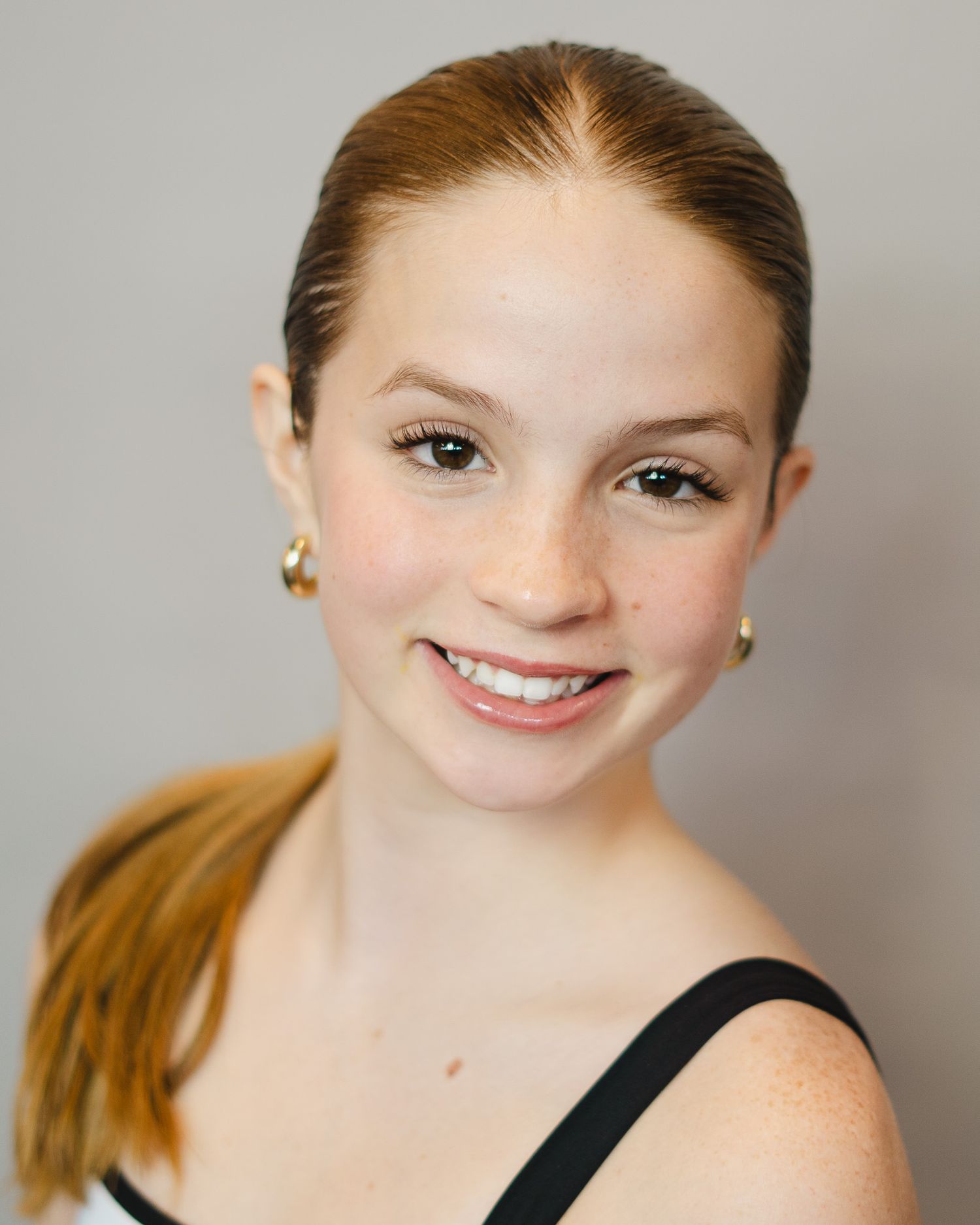 Professional headshot sequence against grey background wearing black tank top.
