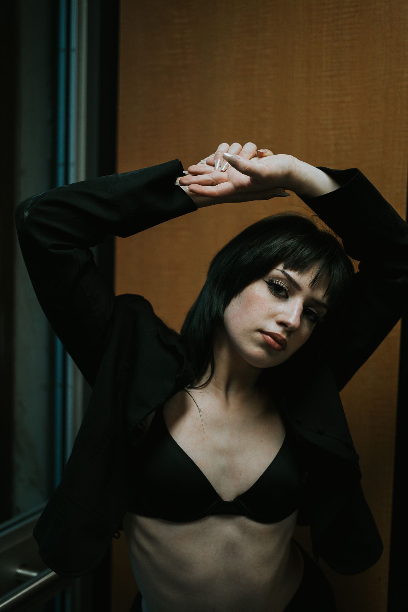 An artistic portrait shows someone in black clothing posing with raised arms.