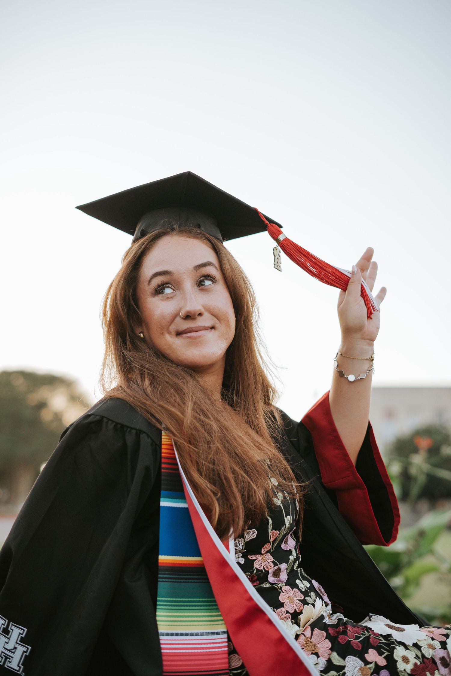 Graduation photos outdoors with decorative cap and gown.