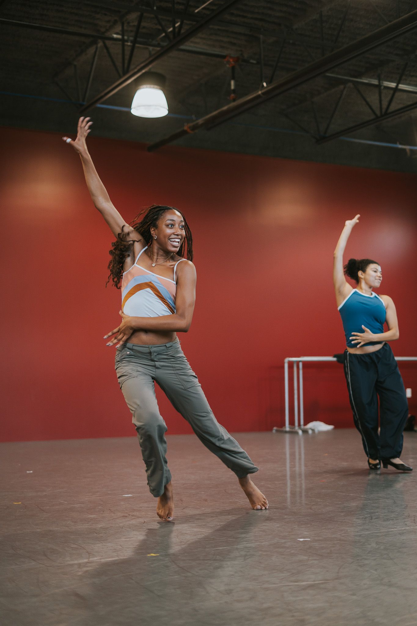 Modern dancers perform expressive movements in a dance studio with red walls.