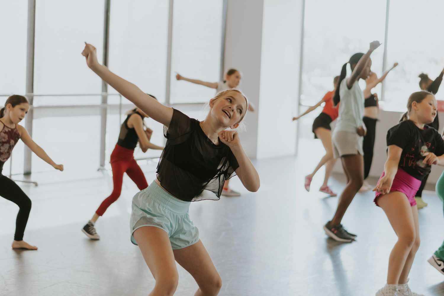 Dancers in casual attire practicing contemporary dance moves in a bright studio setting.