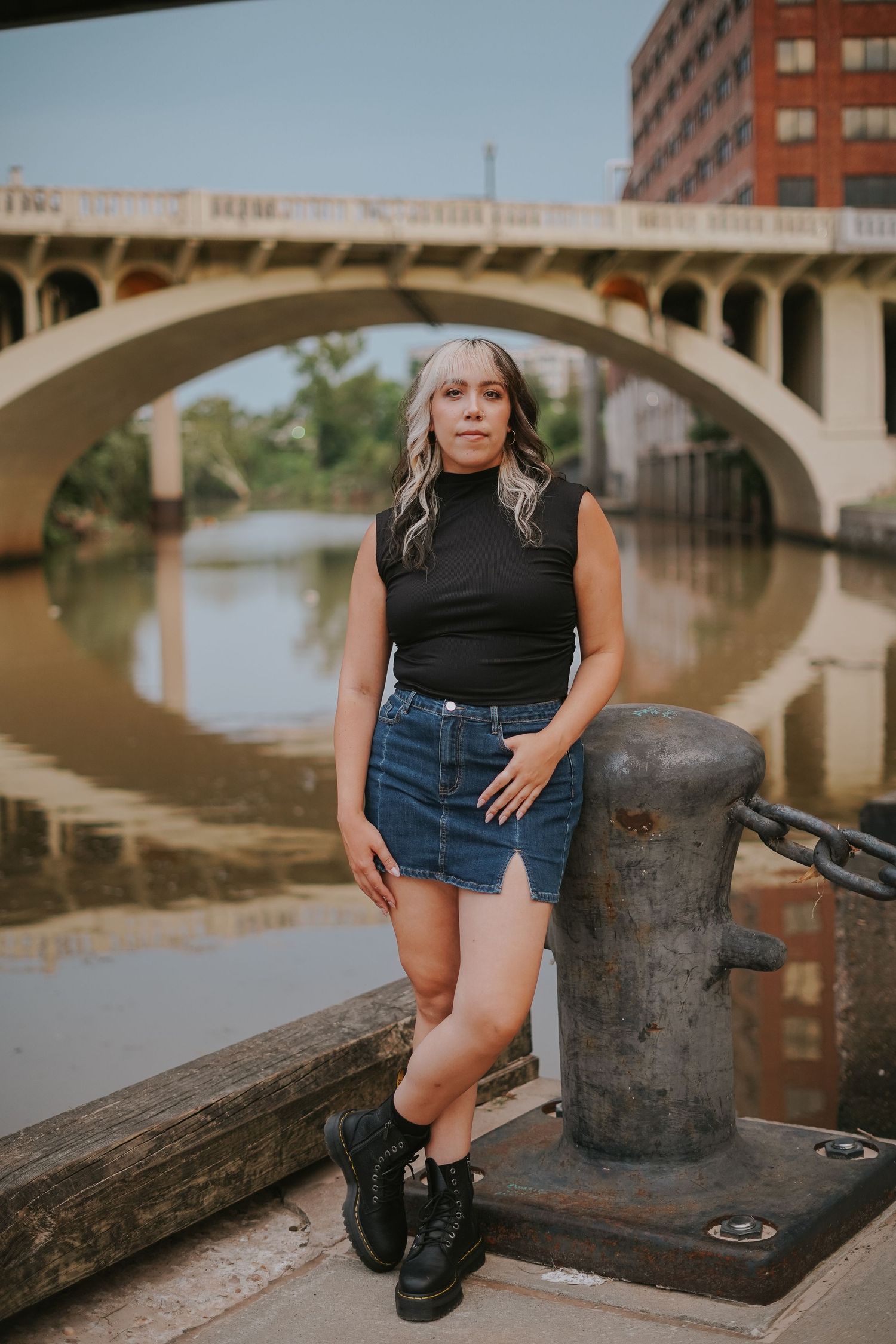 Urban portraits by river with architecture and bridge in background.