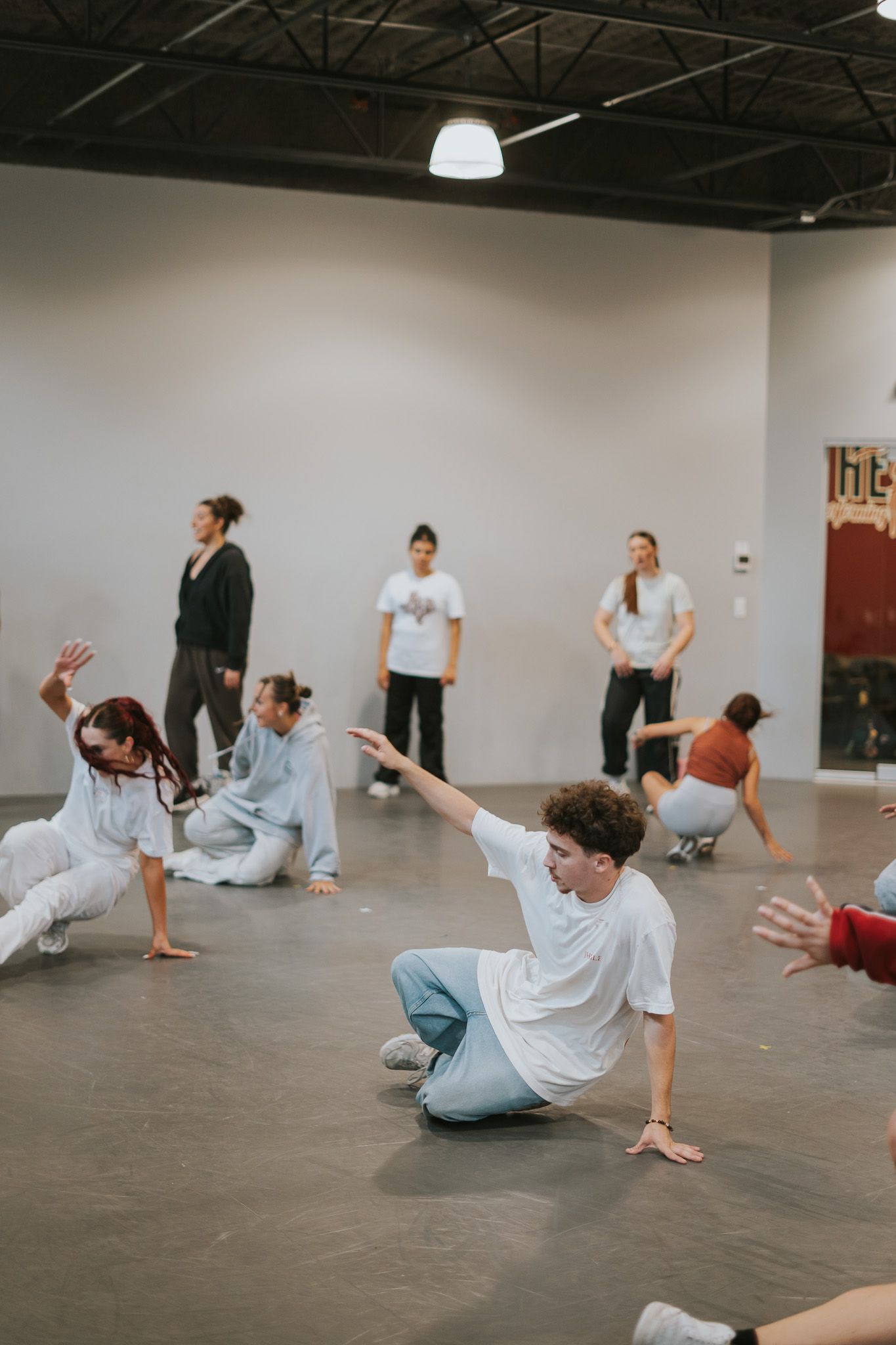 Dancers practice floor movements during a contemporary dance class in a studio space.