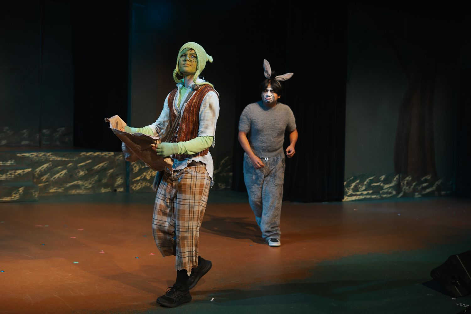 Two actors perform on stage as Shrek and Donkey in a theatrical production of Shrek the Musical.