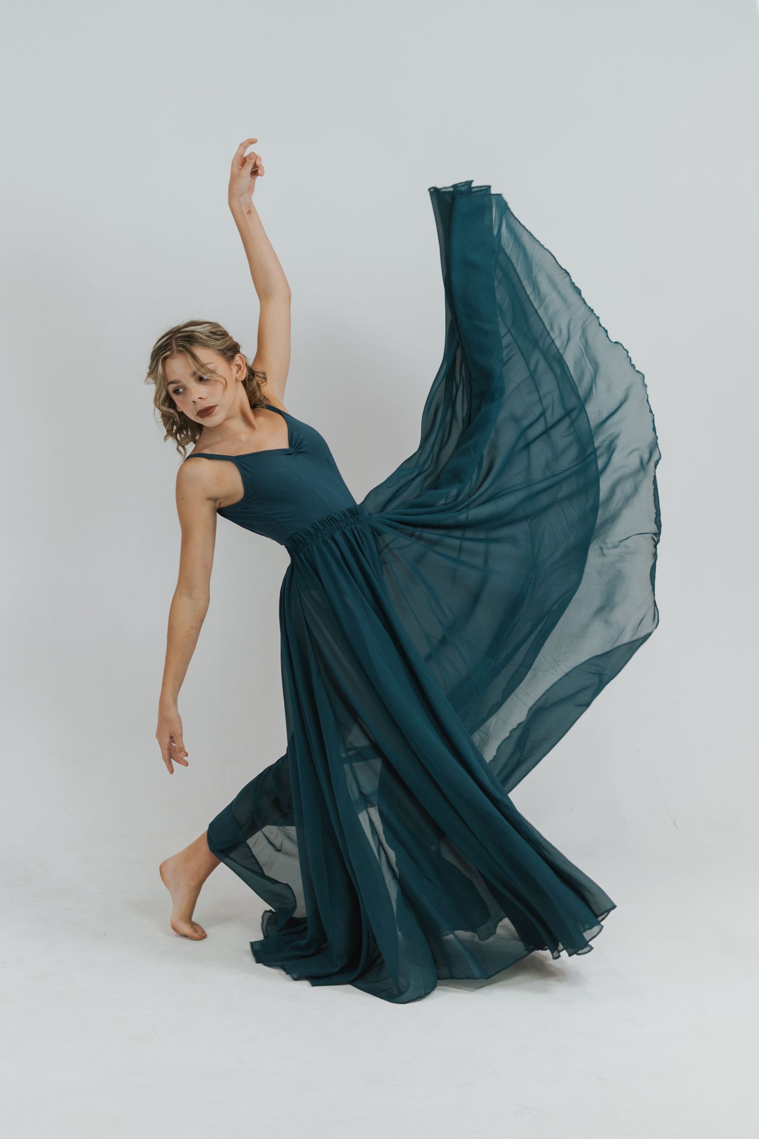 Dancer in flowing navy blue dress creates elegant motion sequence against white background in four artistic poses.