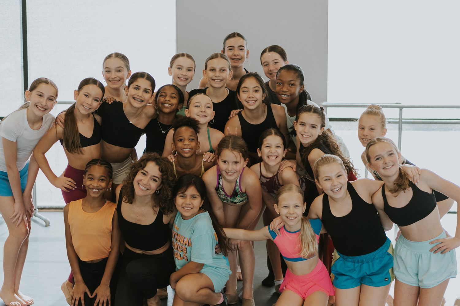Group of dancers in athletic wear posing together in a dance studio.