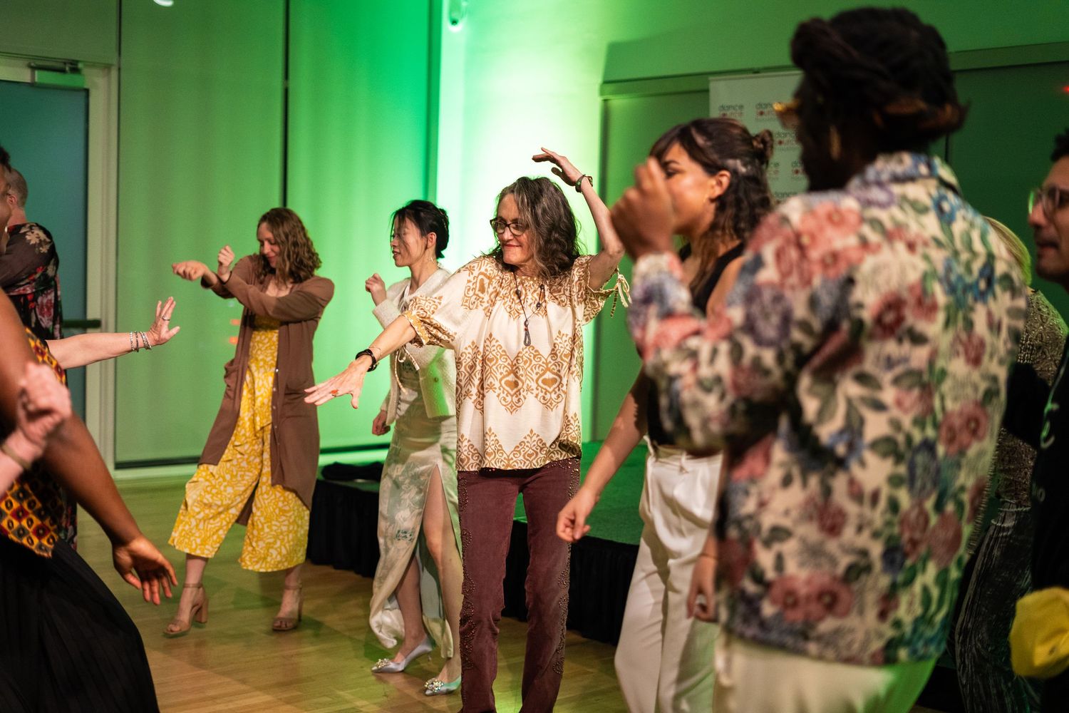 People enjoying a group dance session in a room with green-lit walls.