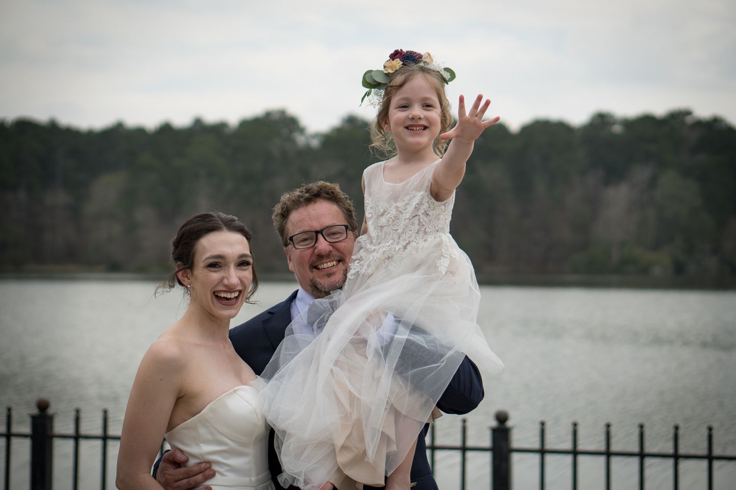 Candid wedding party celebrations by a lakeside setting.